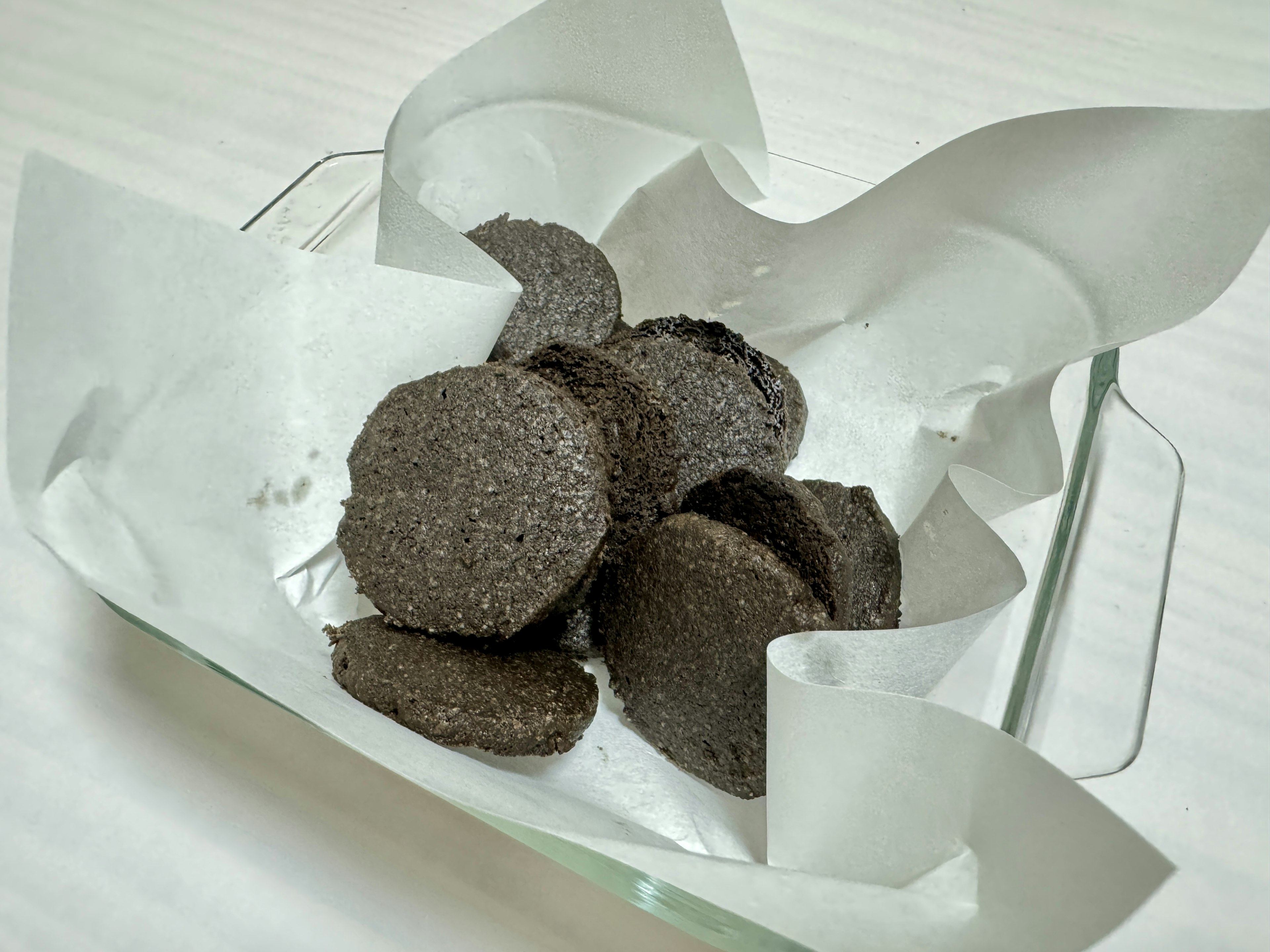 A plate with black cookies wrapped in white parchment paper