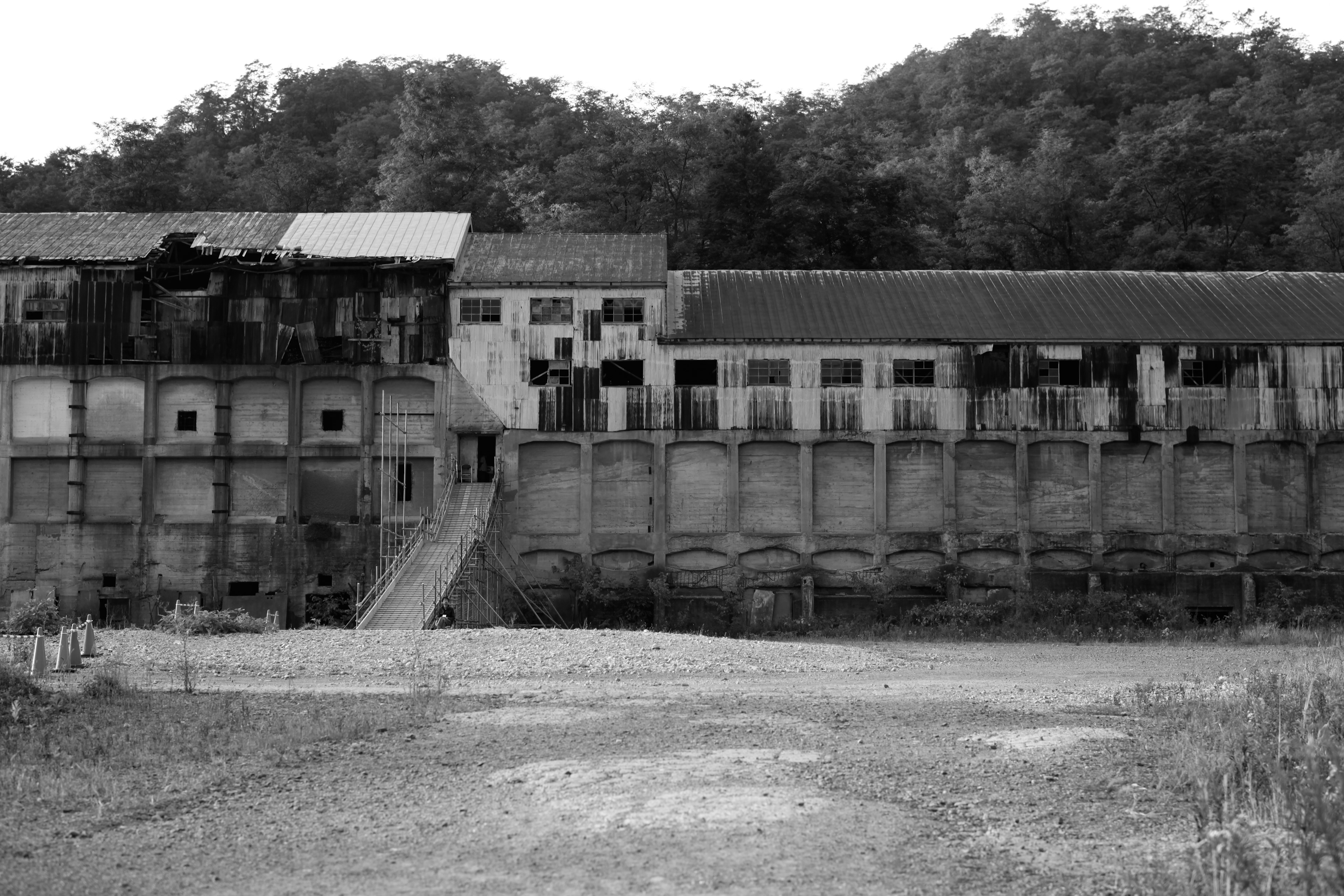 Abandoned building complex with a staircase and surrounding forest