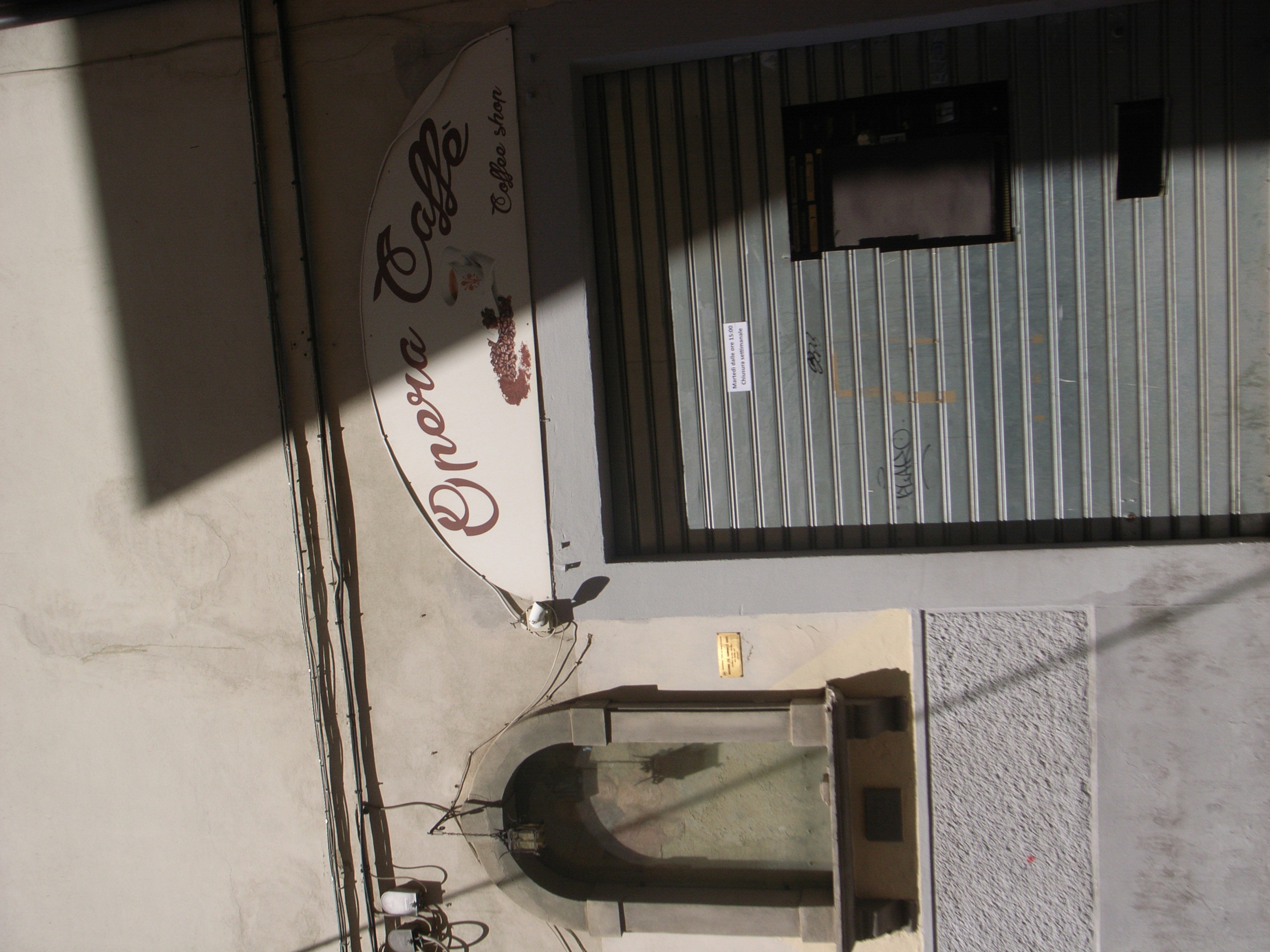 Exterior de un café con un letrero persiana a rayas y una fuente decorativa