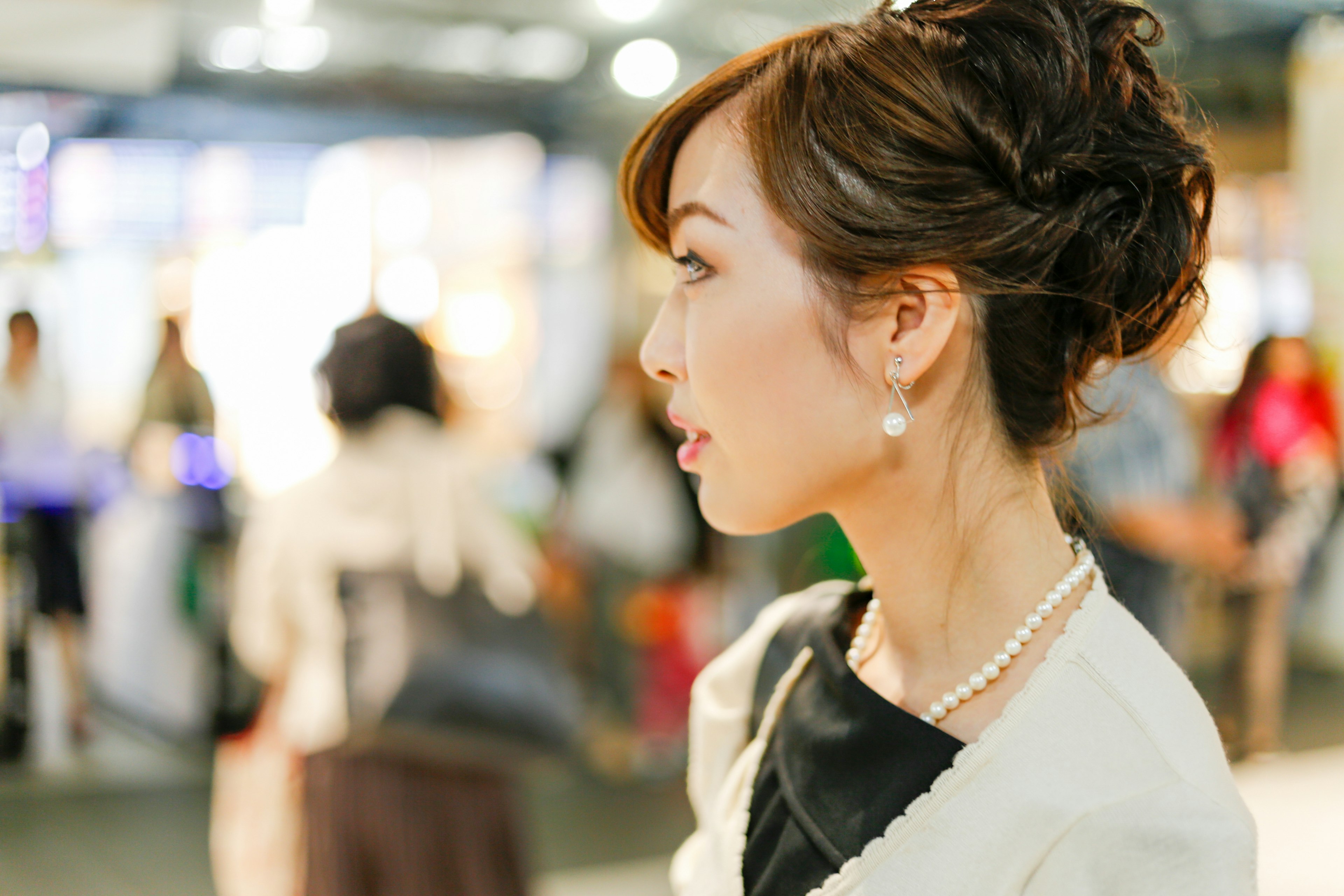 Gambar wanita dengan rambut diikat elegan dan anting mutiara dari samping