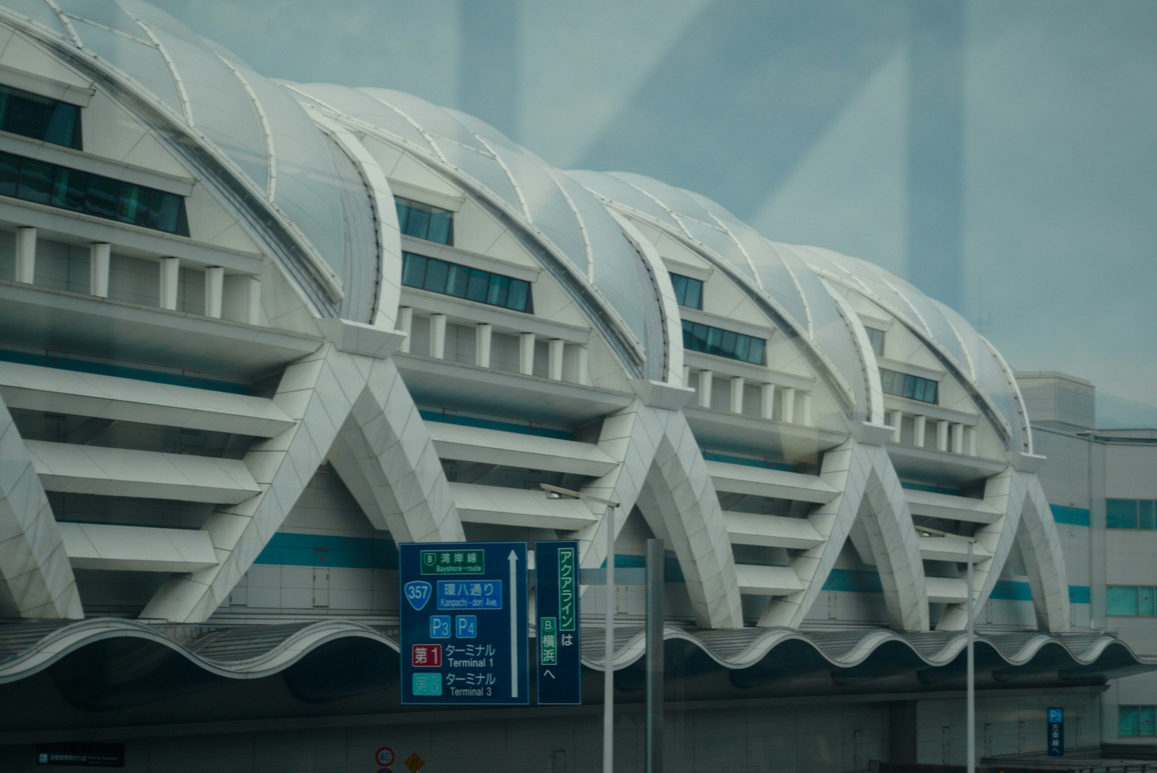 Futuristic airport building exterior with linear roof patterns and bright blue signage