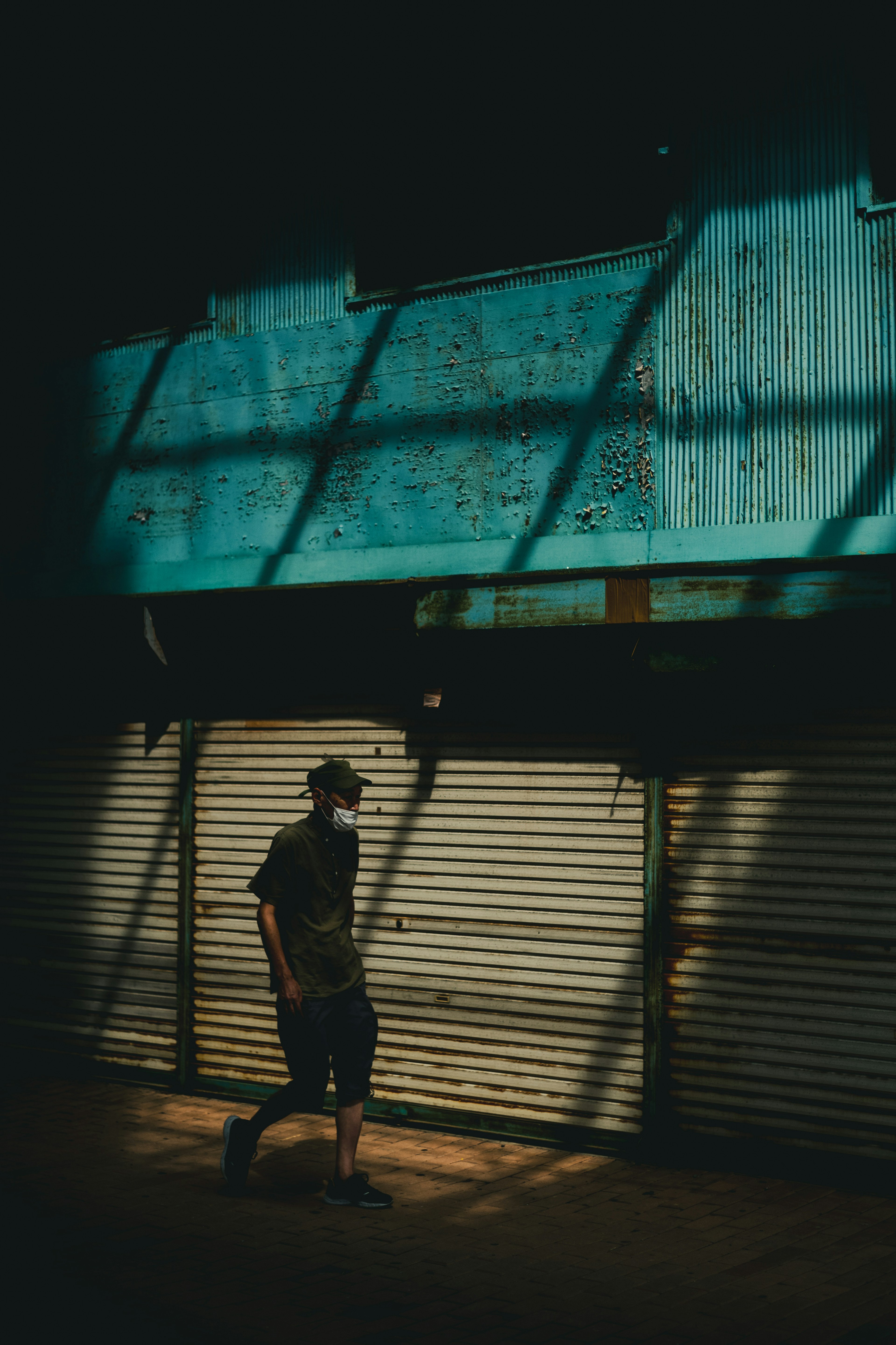 Homme marchant dans une ruelle sombre avec des ombres d'un mur bleu