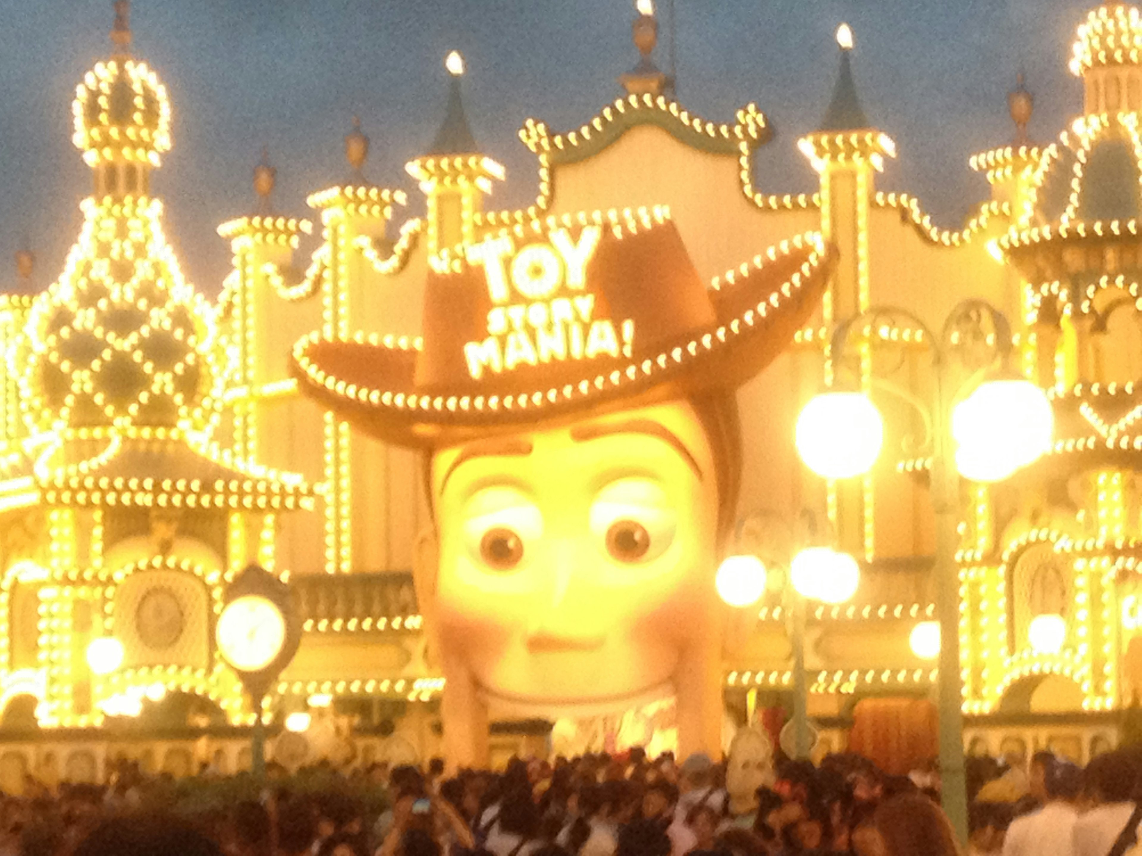 Giant Woody face from Toy Story illuminated at a nighttime amusement park