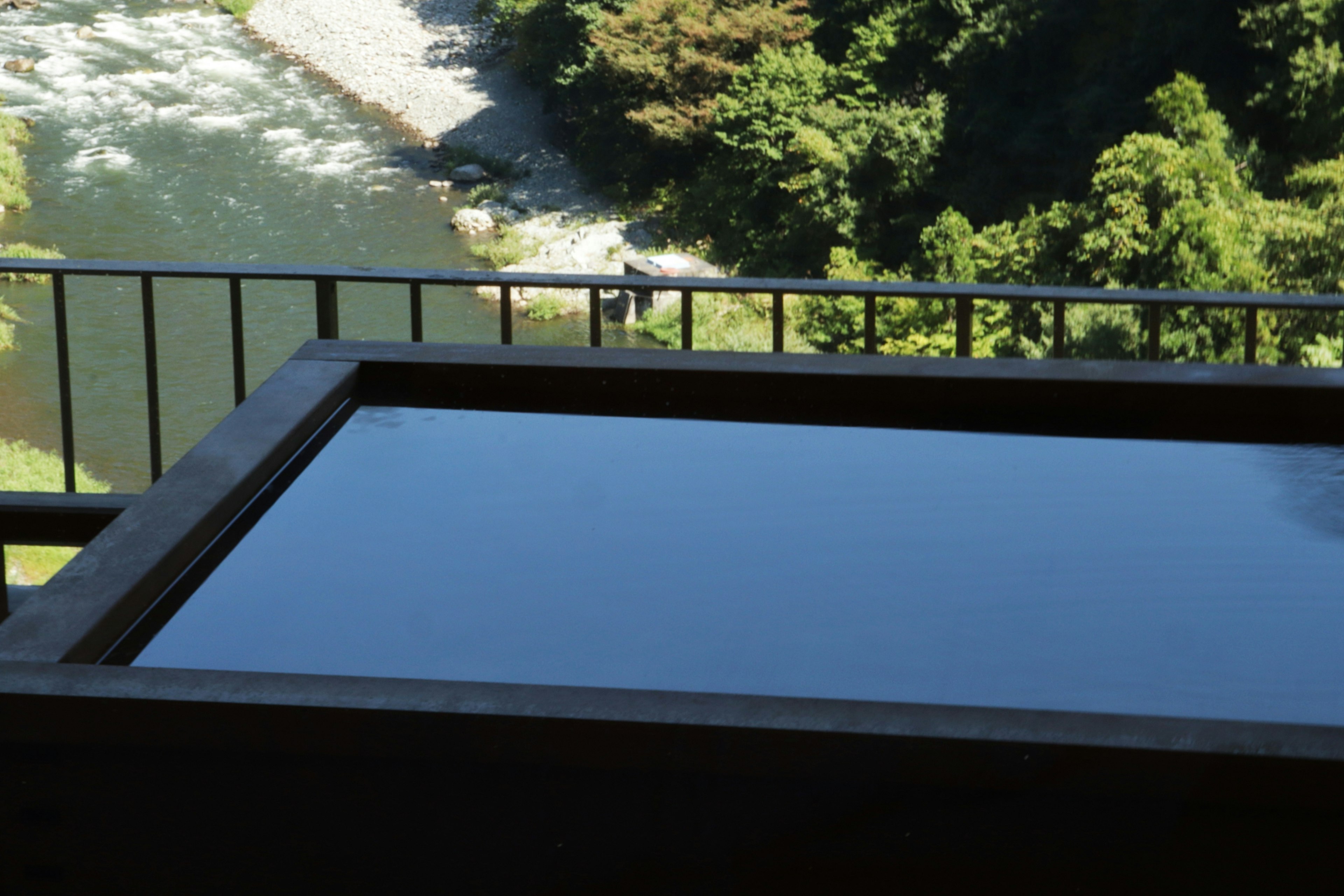 Wooden hot spring bath on a balcony overlooking a river view