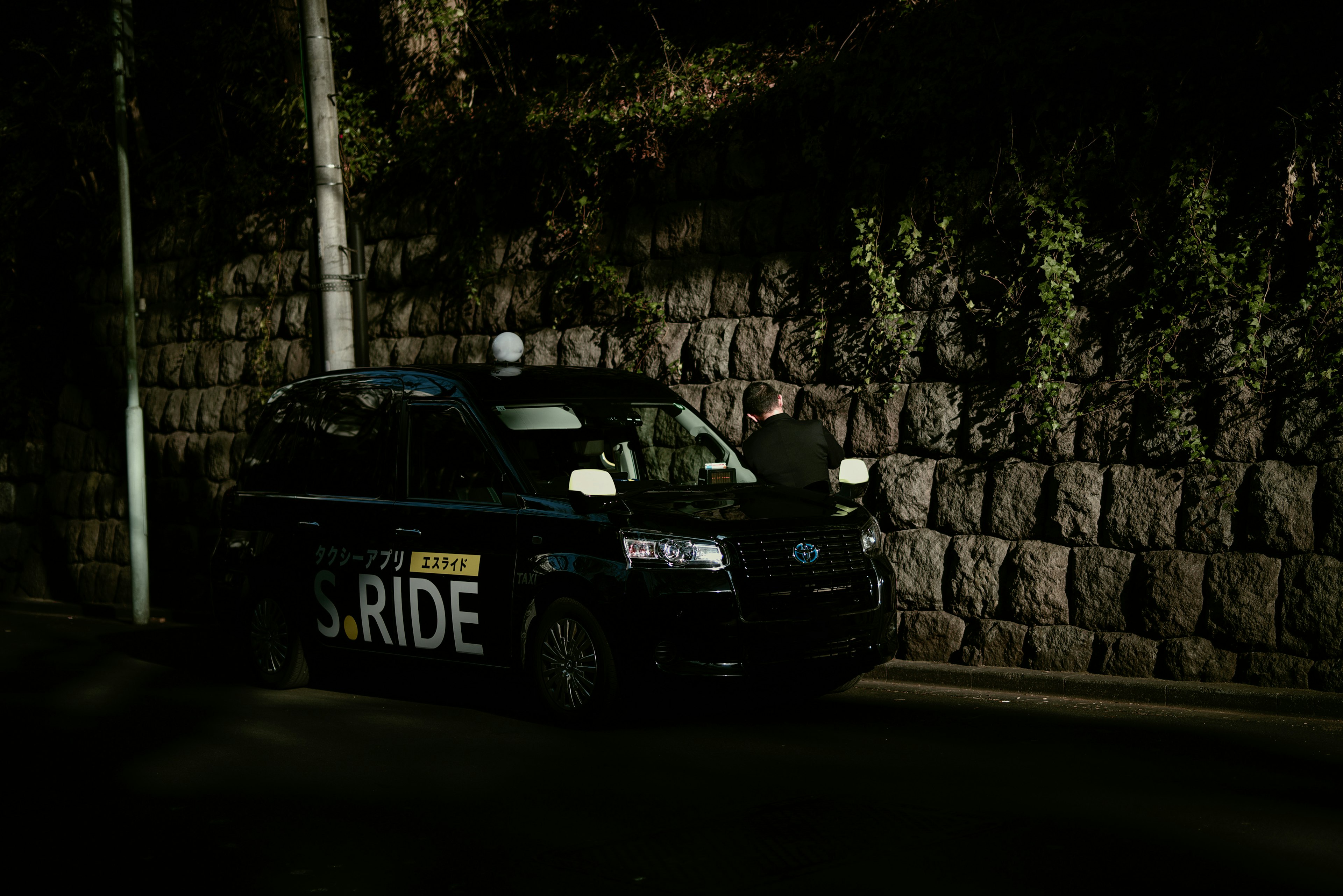 Auto della polizia parcheggiata in una strada buia accanto a un muro di pietra