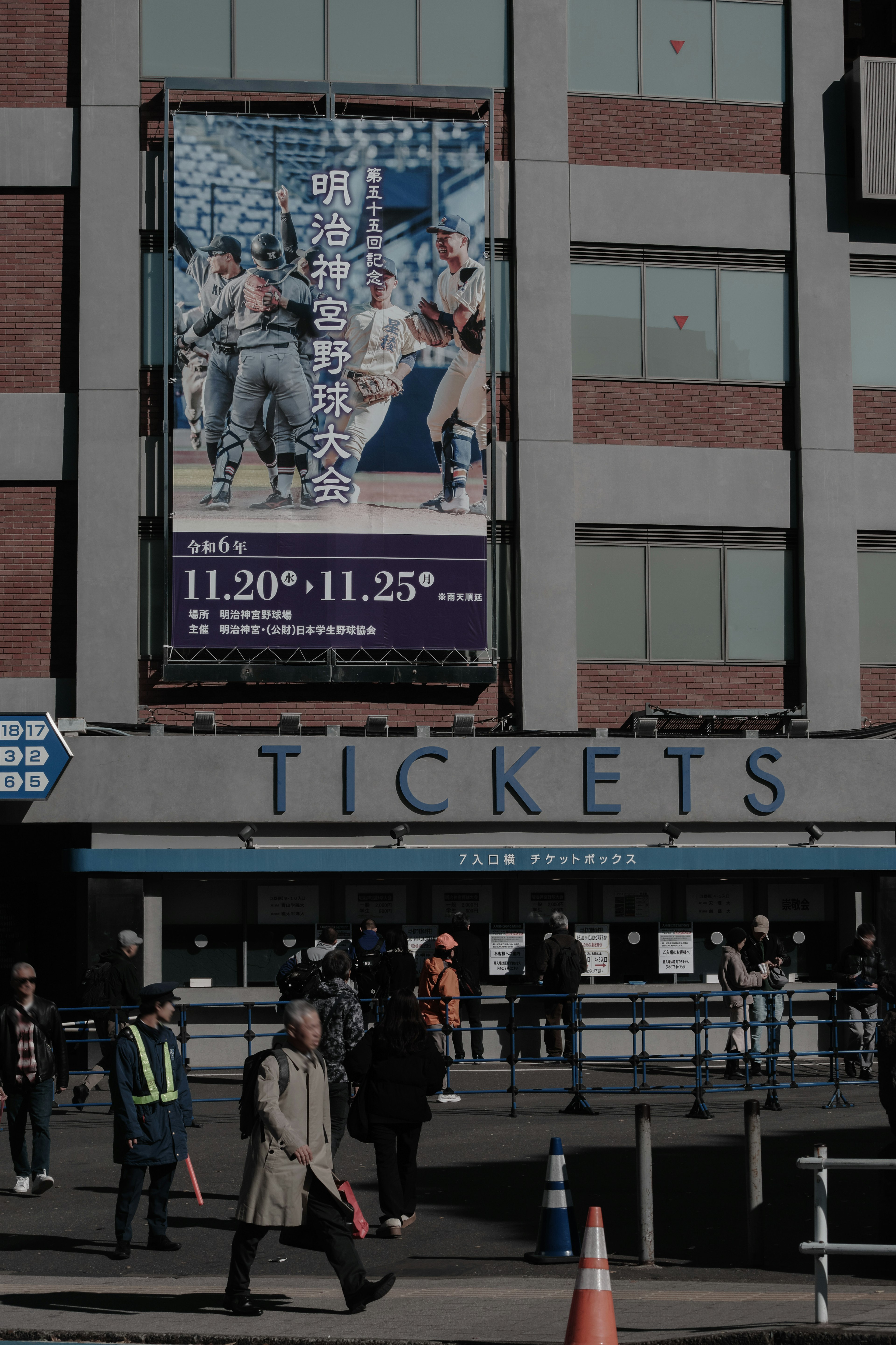 Ticket booth with people passing by and a promotional banner