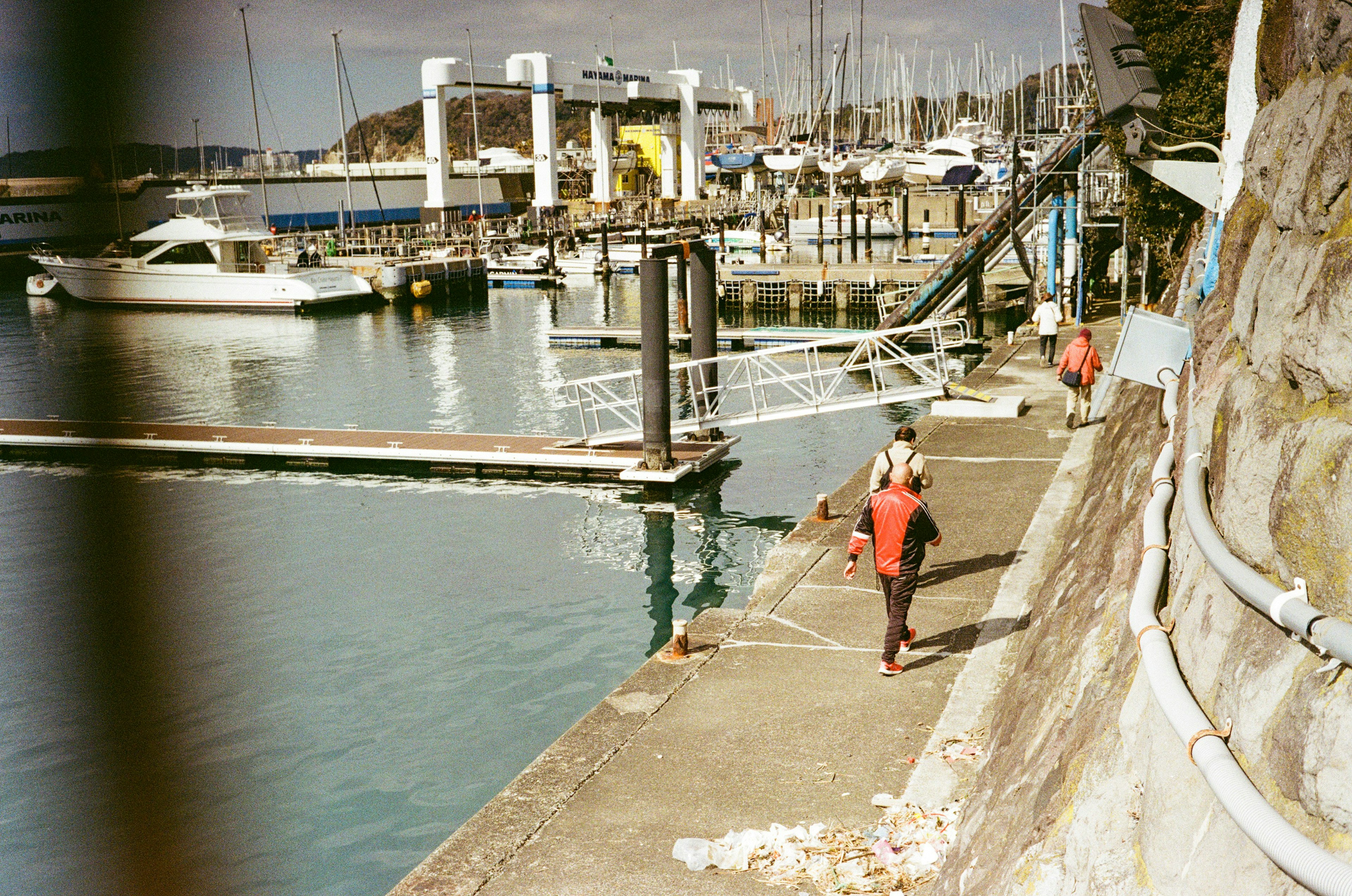 People working on a pier by the sea with boats in the background