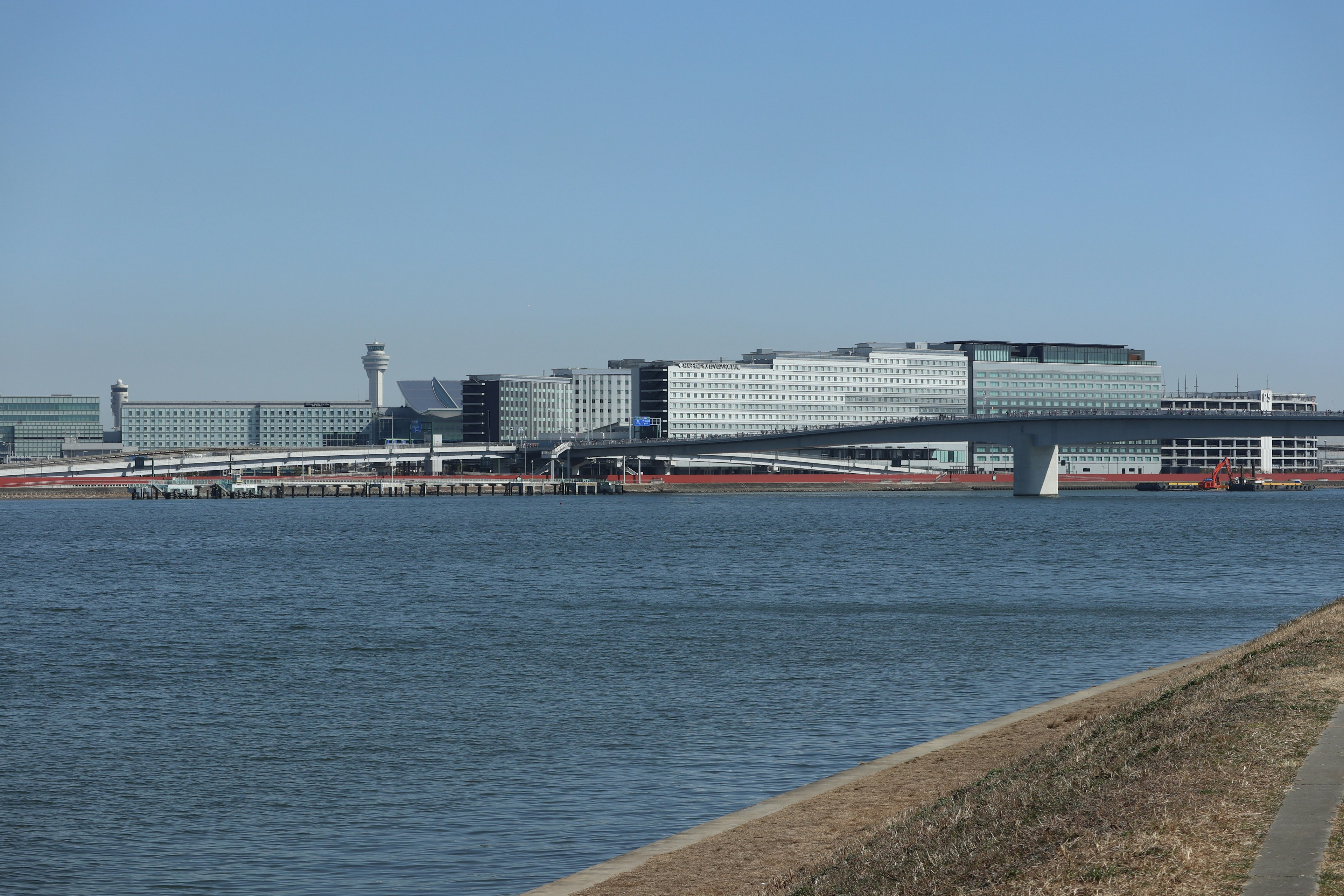 Vista de un edificio de aeropuerto moderno y de la pista a lo largo del río