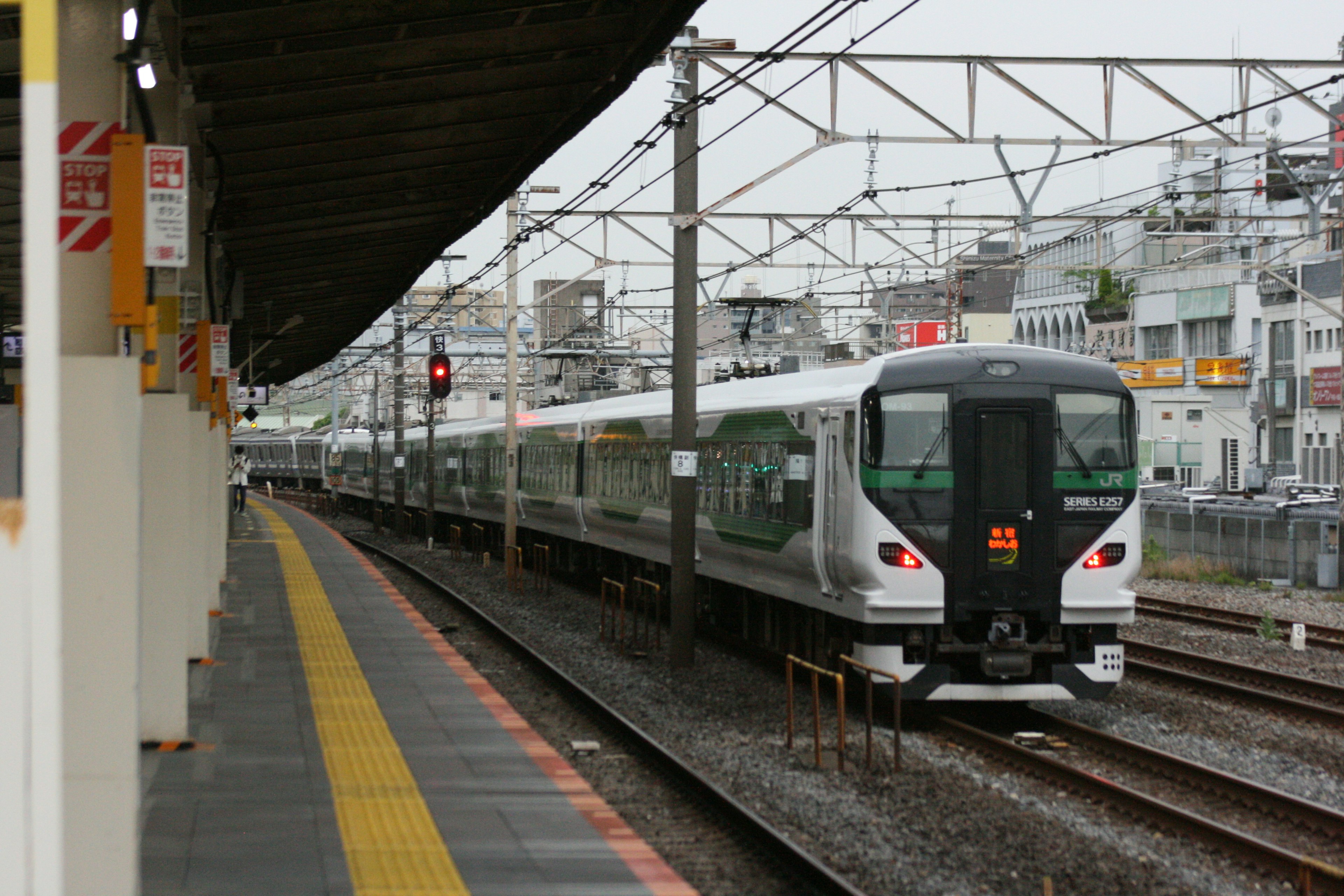 A train arriving at a station featuring railway tracks and a signal light