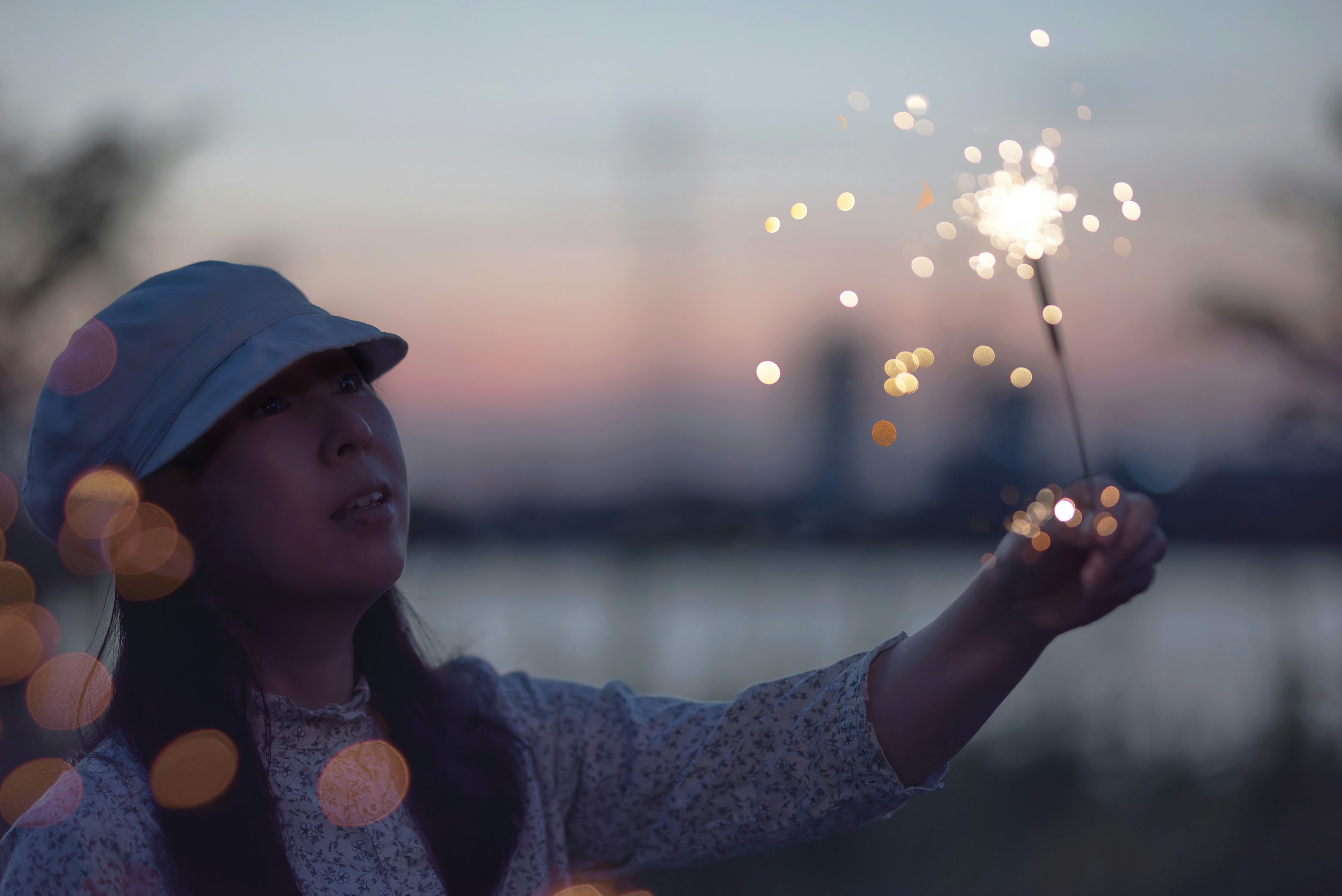 夕暮れの中で手に花火を持つ女性の姿