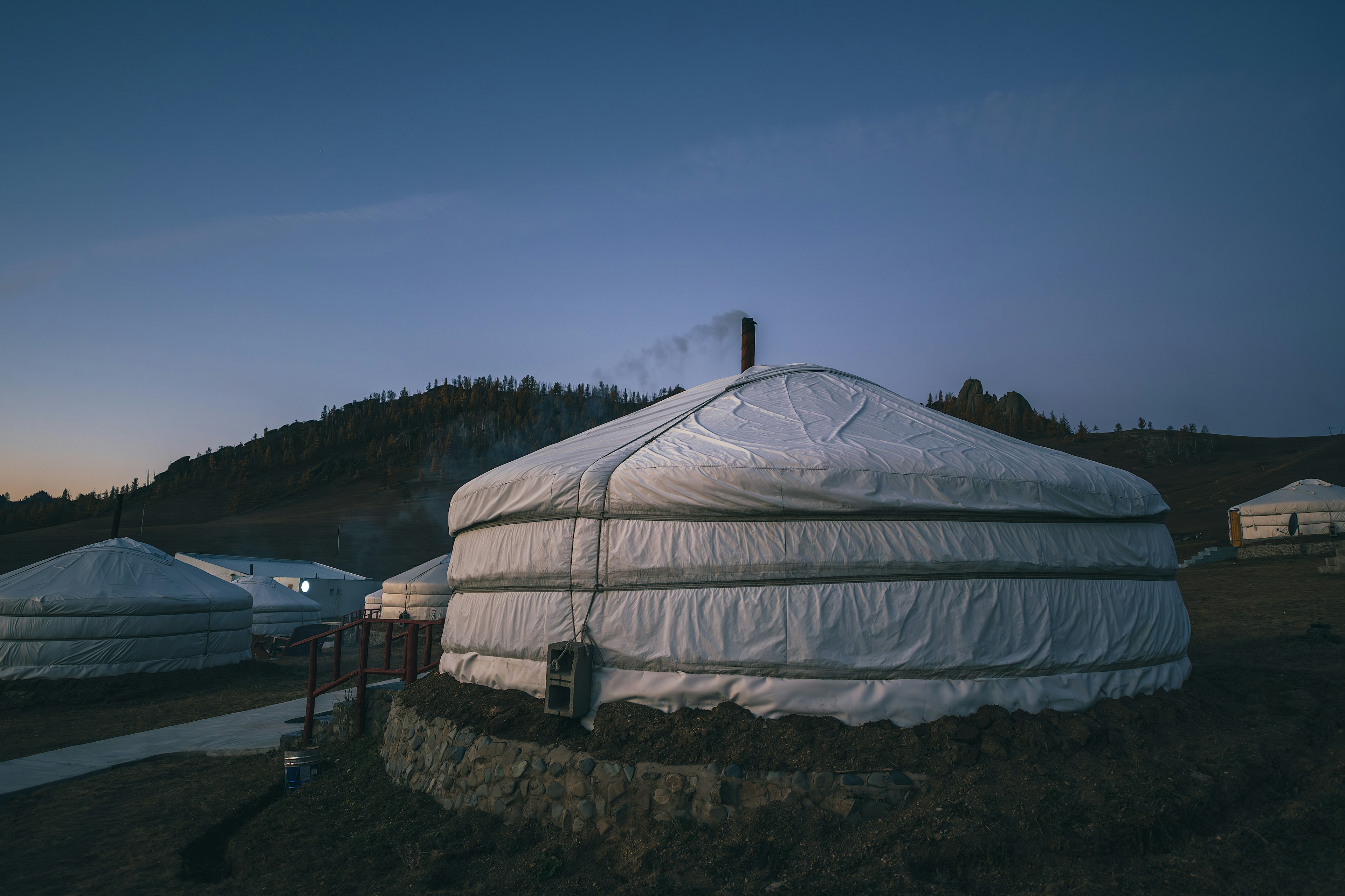 Ger di Mongolia saat senja dengan pegunungan di latar belakang