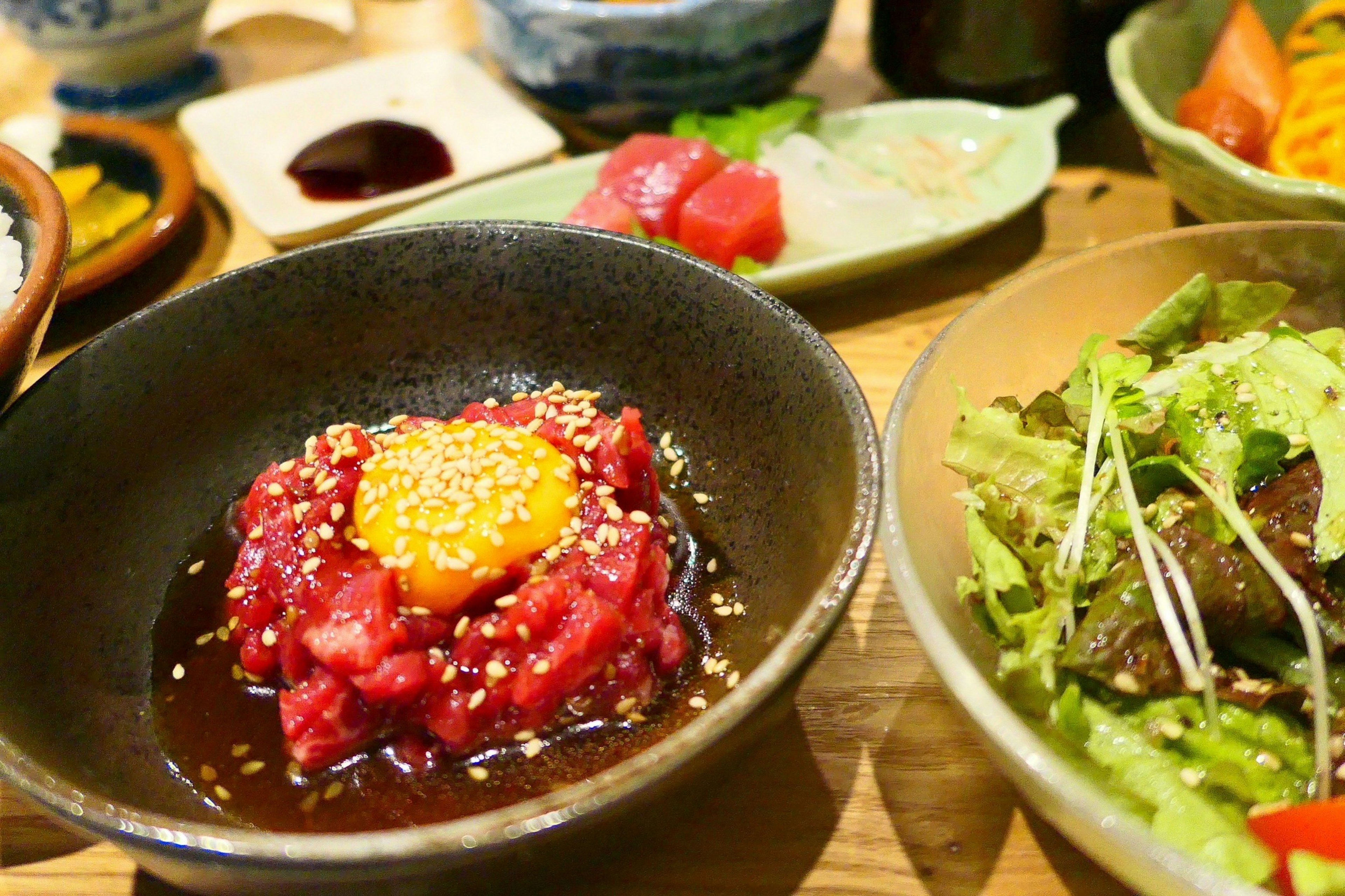 A beautifully presented bowl of raw fish with egg yolk and sesame seeds