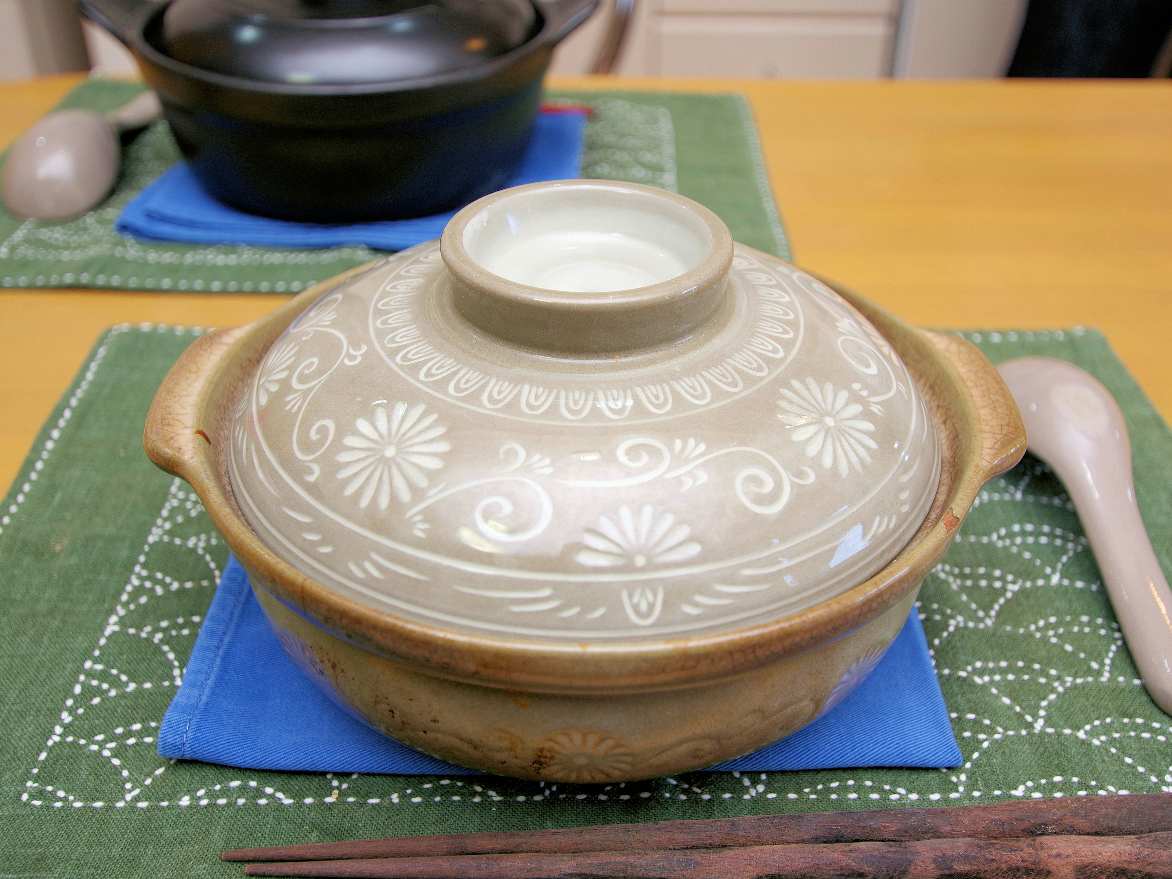 A beautifully decorated ceramic pot placed on a blue cloth