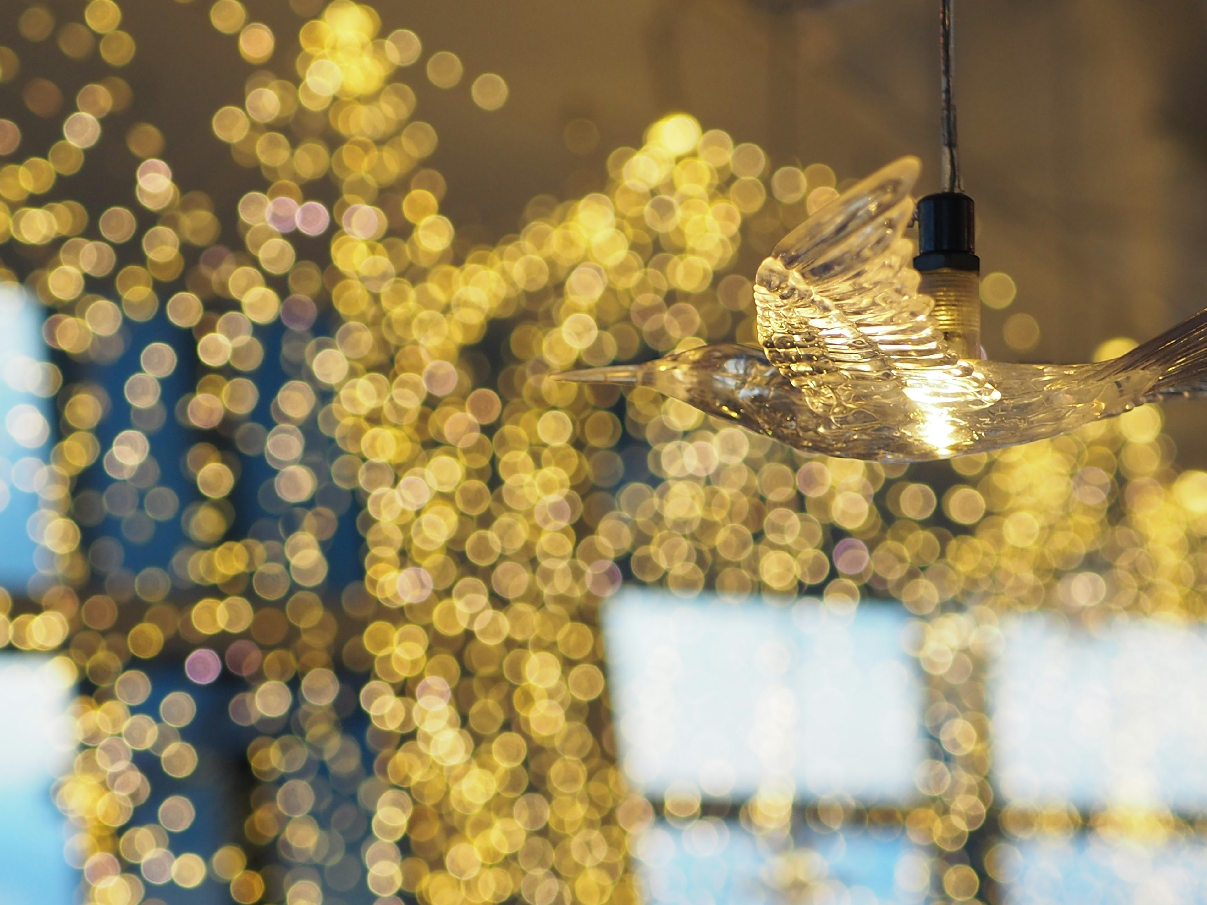 Une lampe en forme d'oiseau transparent illuminée contre un fond de lumière dorée flou