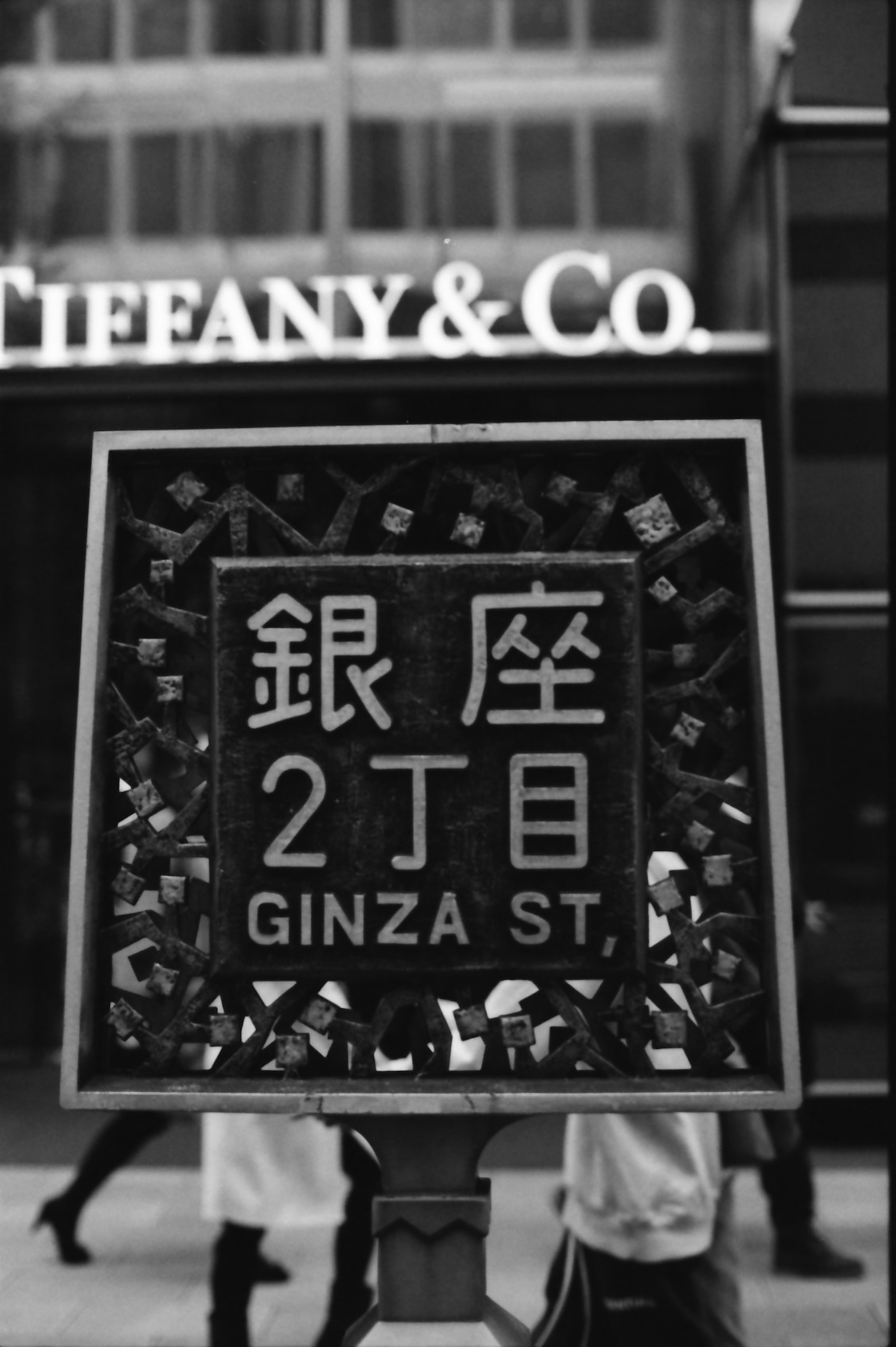 Foto in bianco e nero di un'insegna stradale a Ginza con Tiffany & Co sullo sfondo