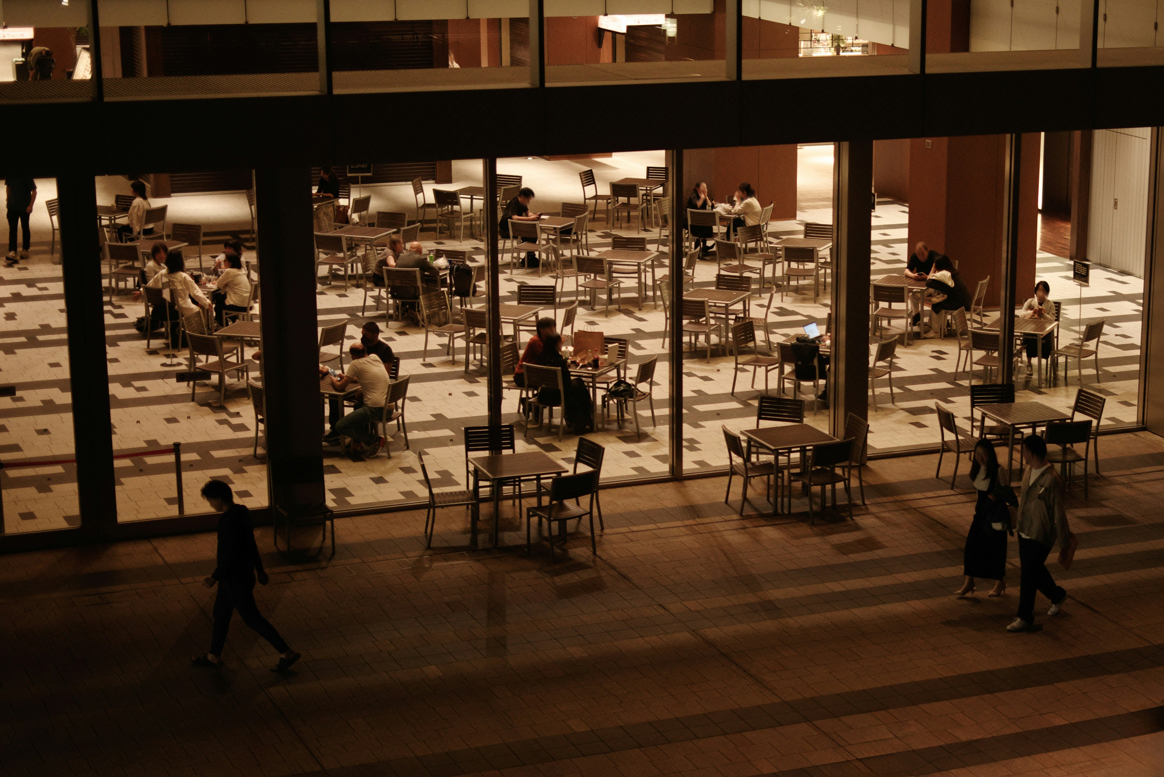 Cafe exterior view tables and chairs visible through windows people seated