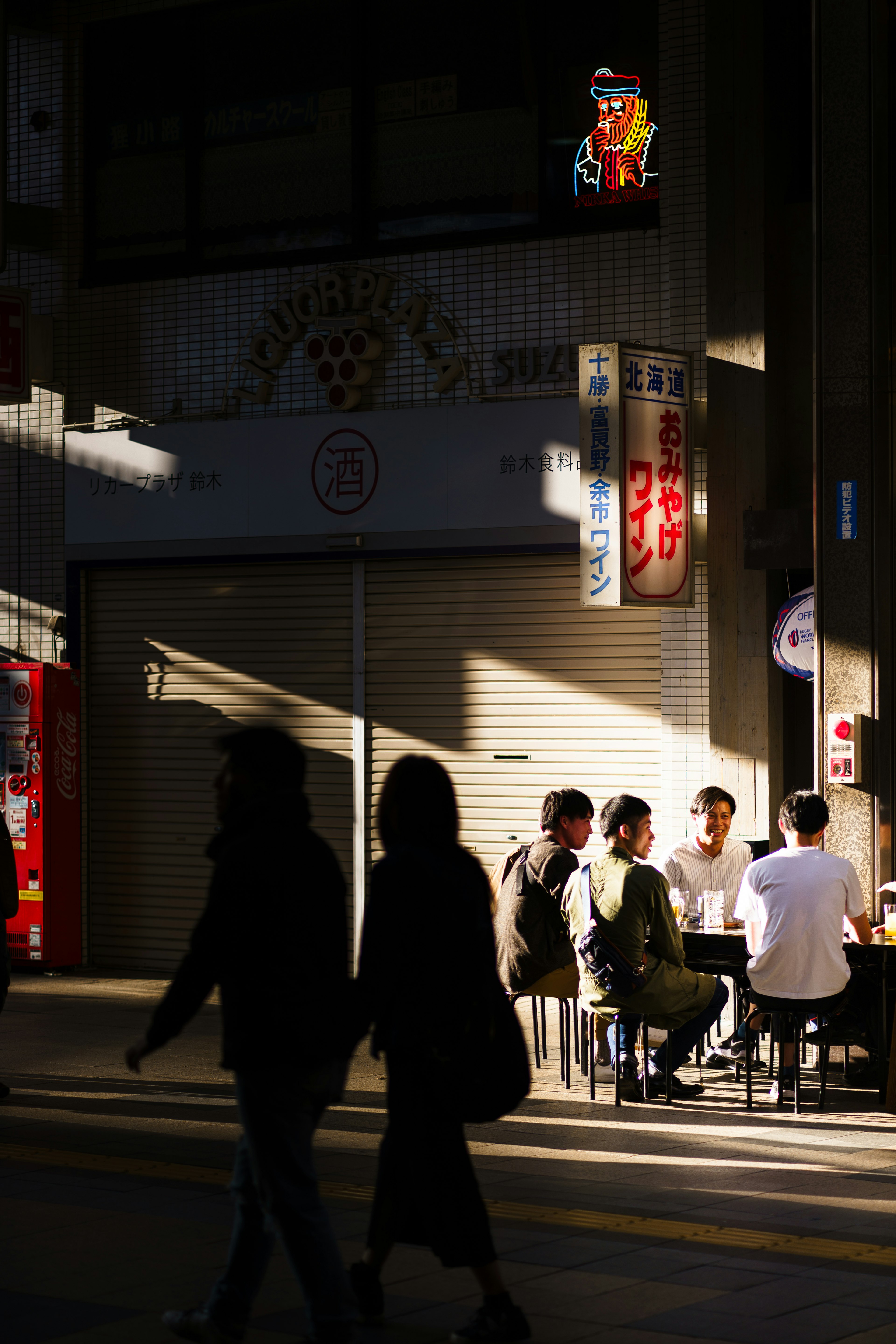 Silhouettes of people walking and sitting in shadows on a city street