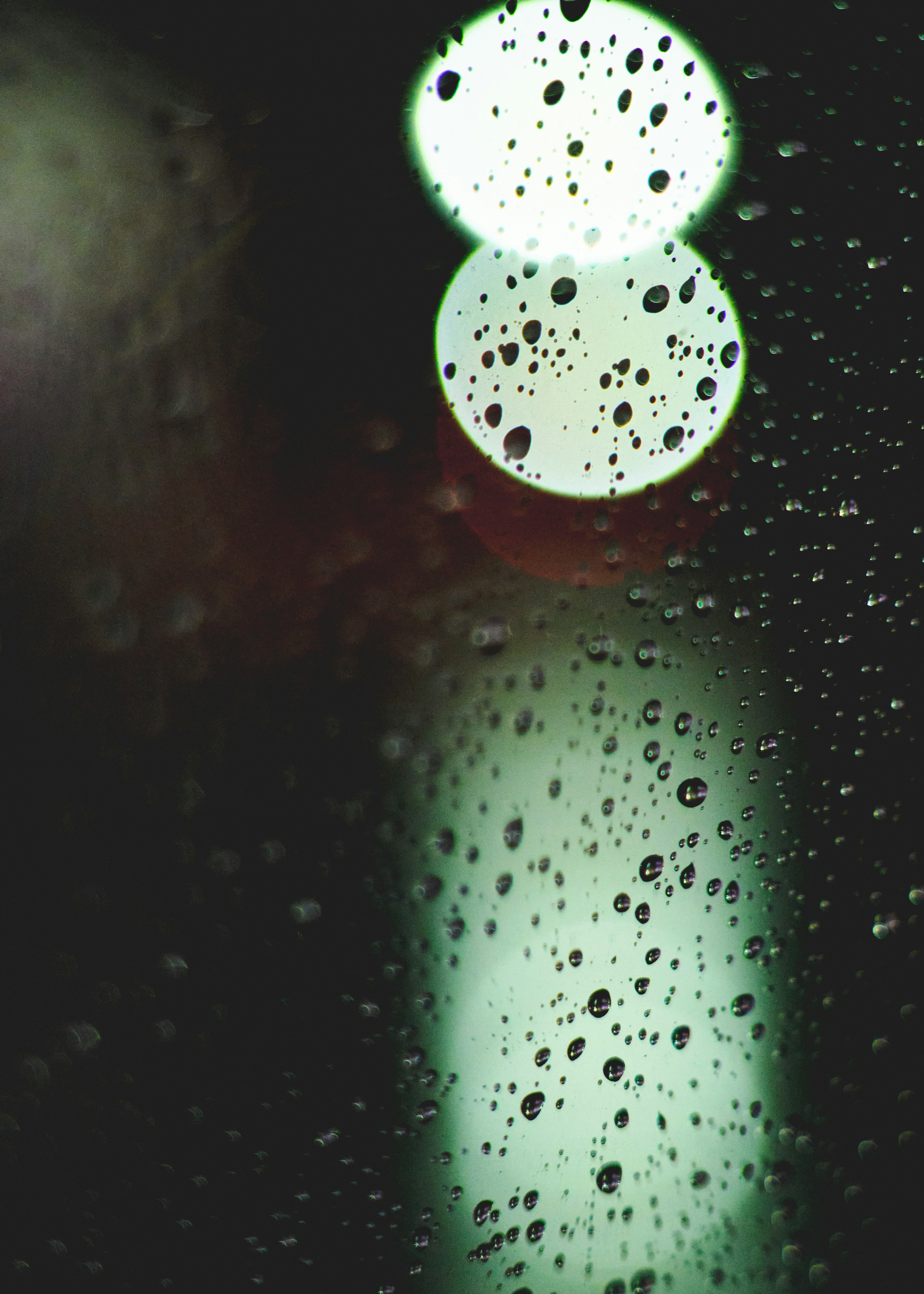 Blurred circular lights seen through raindrops on glass