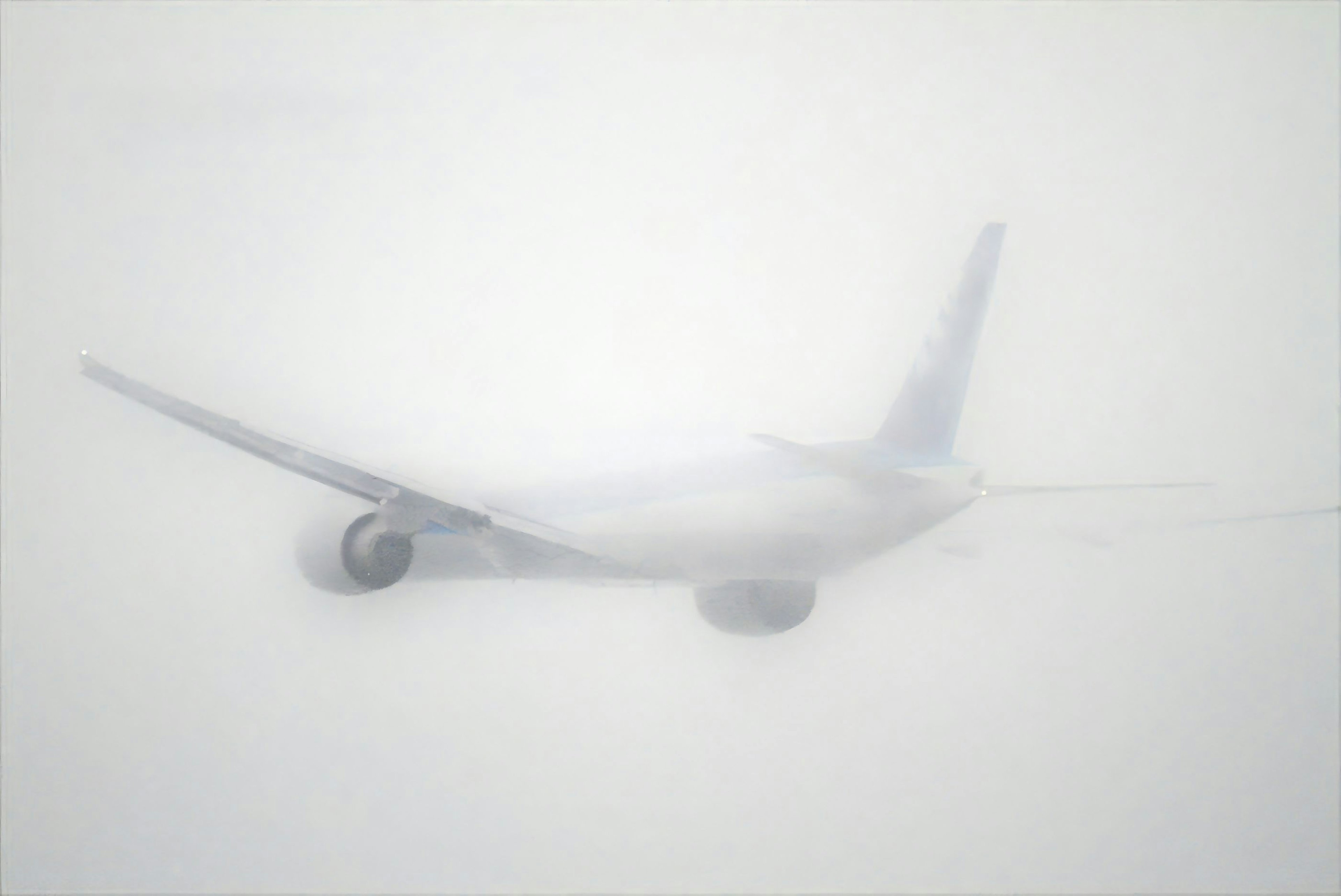 Airplane partially obscured in white fog