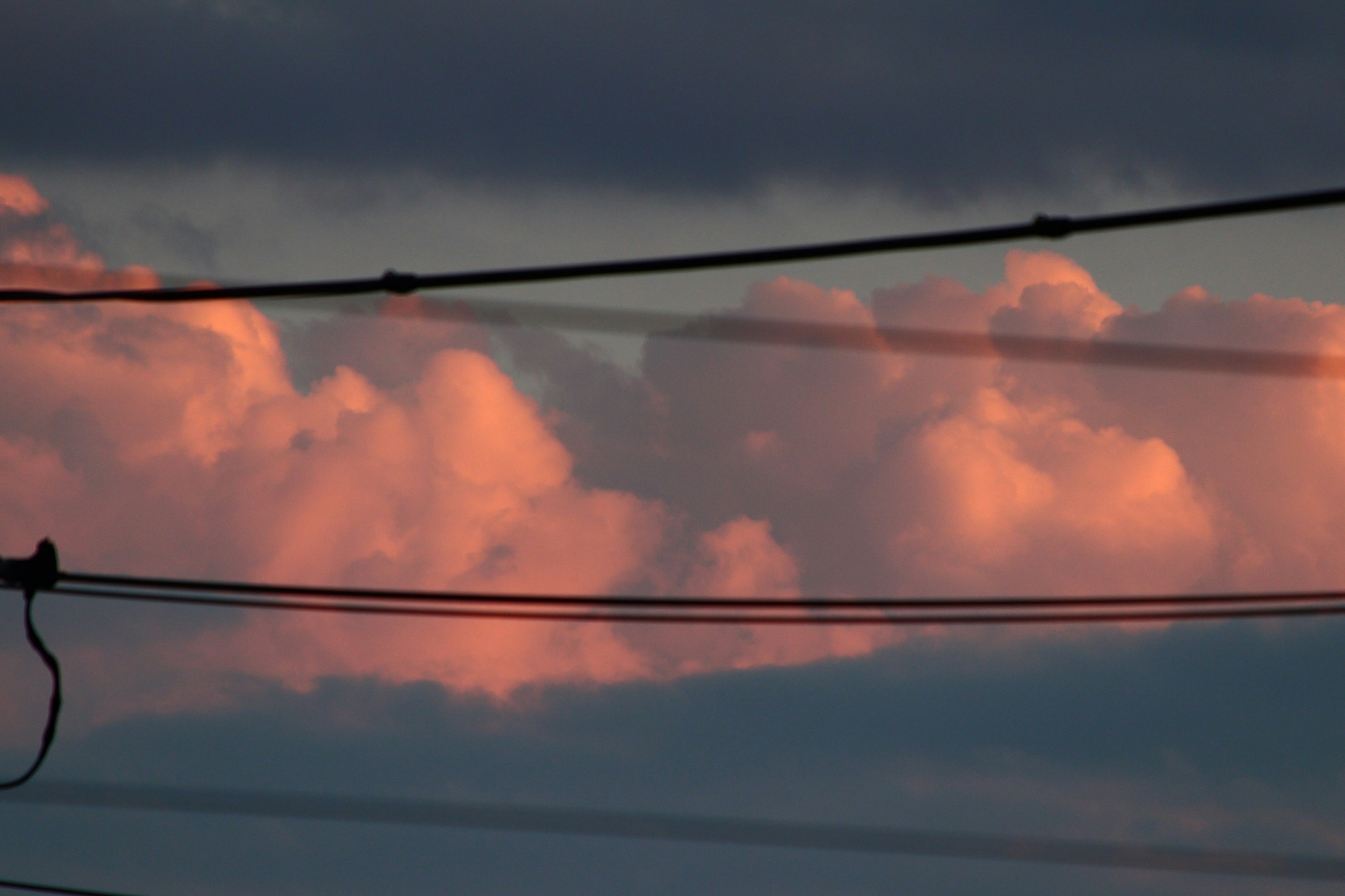 Awan matahari terbenam dengan kabel listrik di latar depan