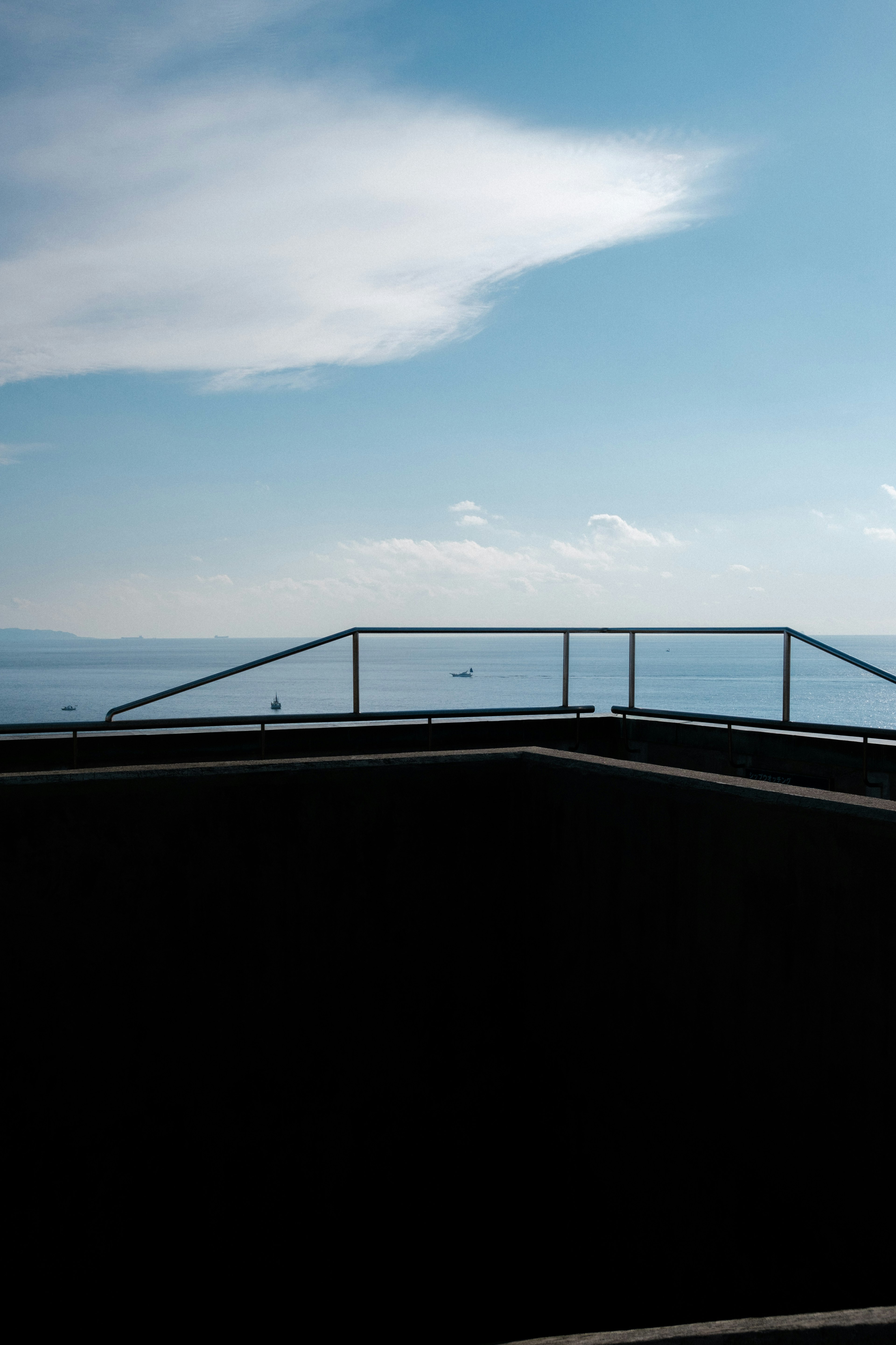 青空と海を背景にした手すりのある屋上の風景