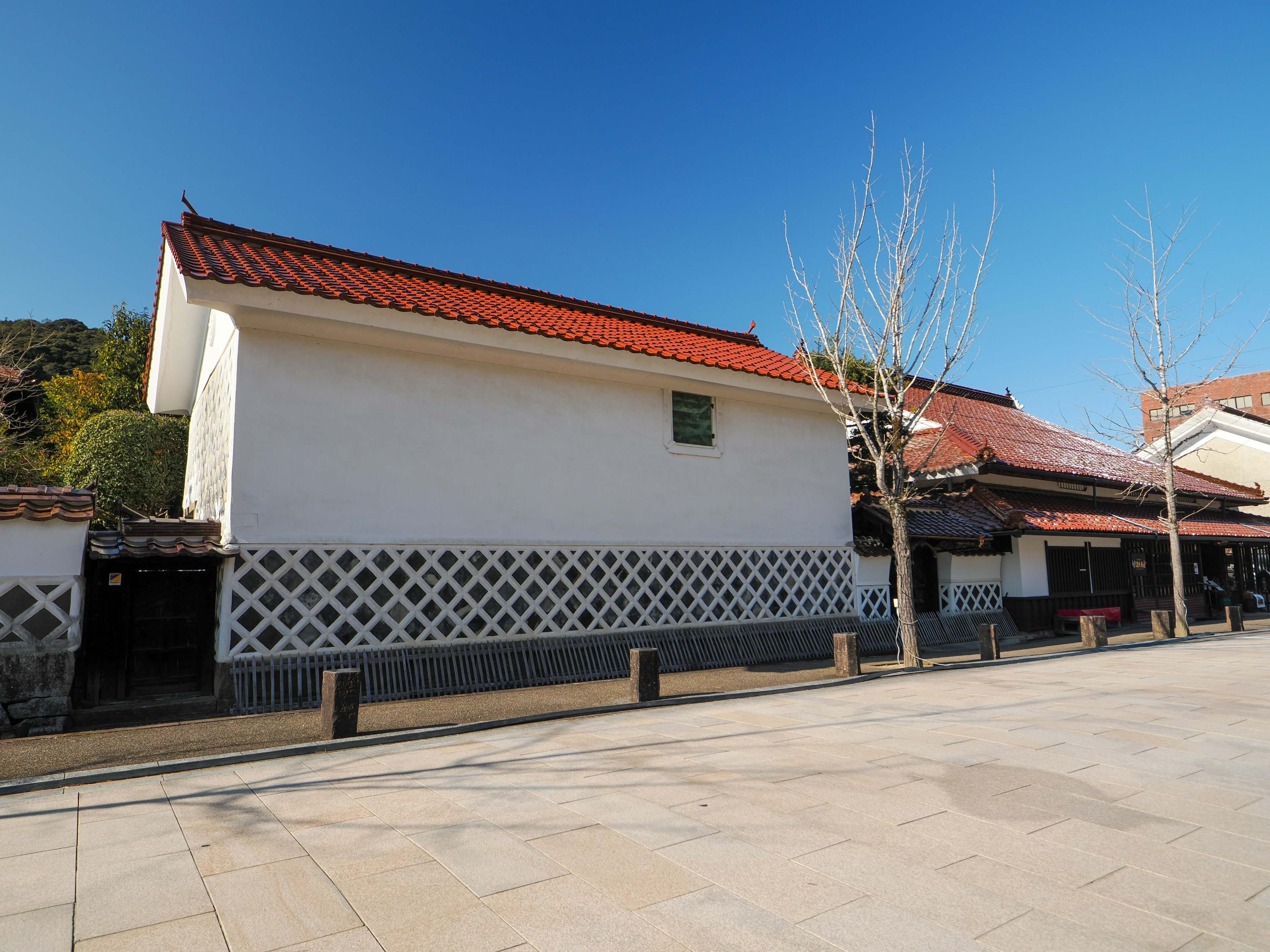 Traditionelles Gebäude mit weißen Wänden und rotem Dach vor klarem blauen Himmel