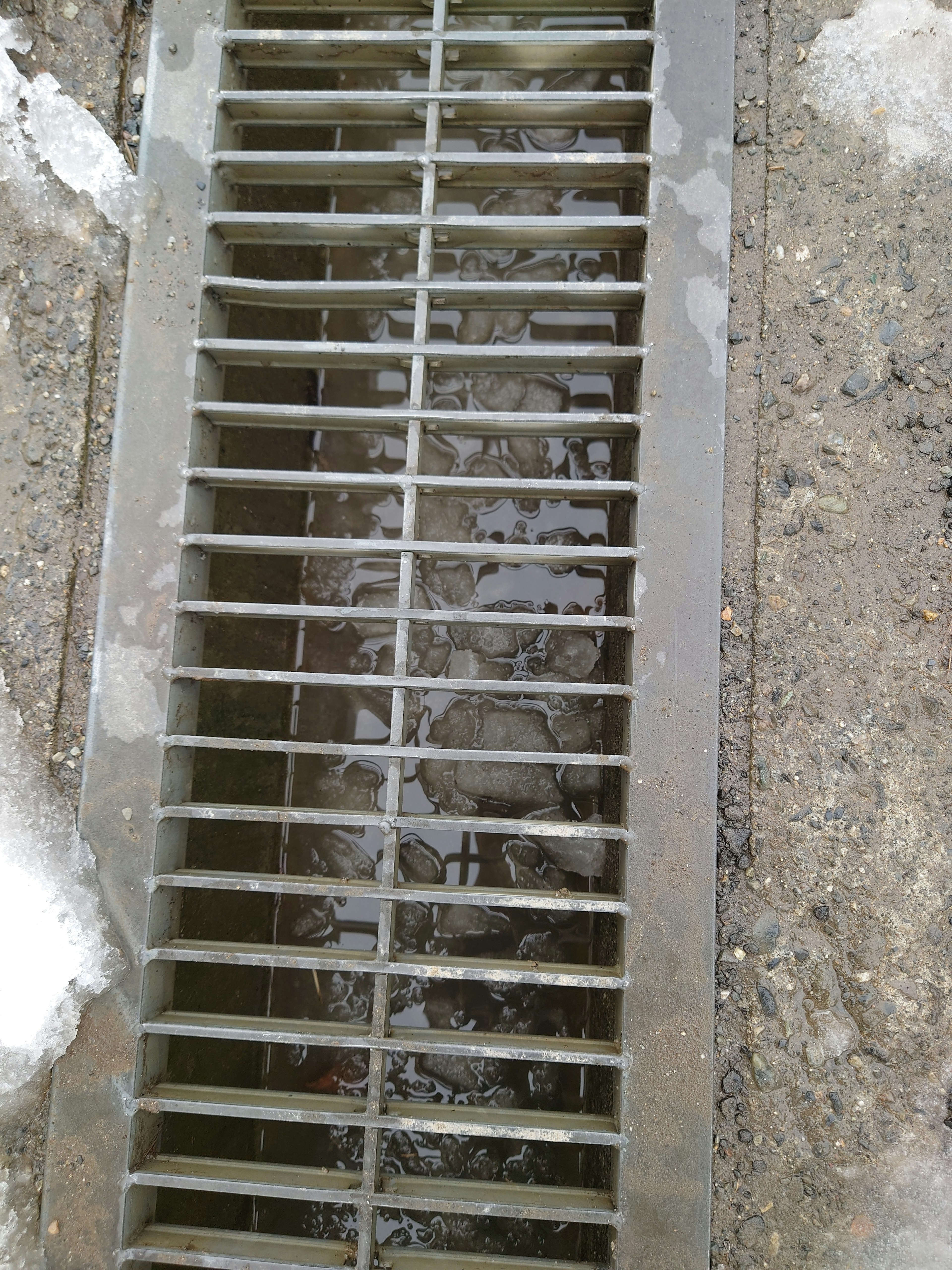 Drainage grate with visible water flowing underneath