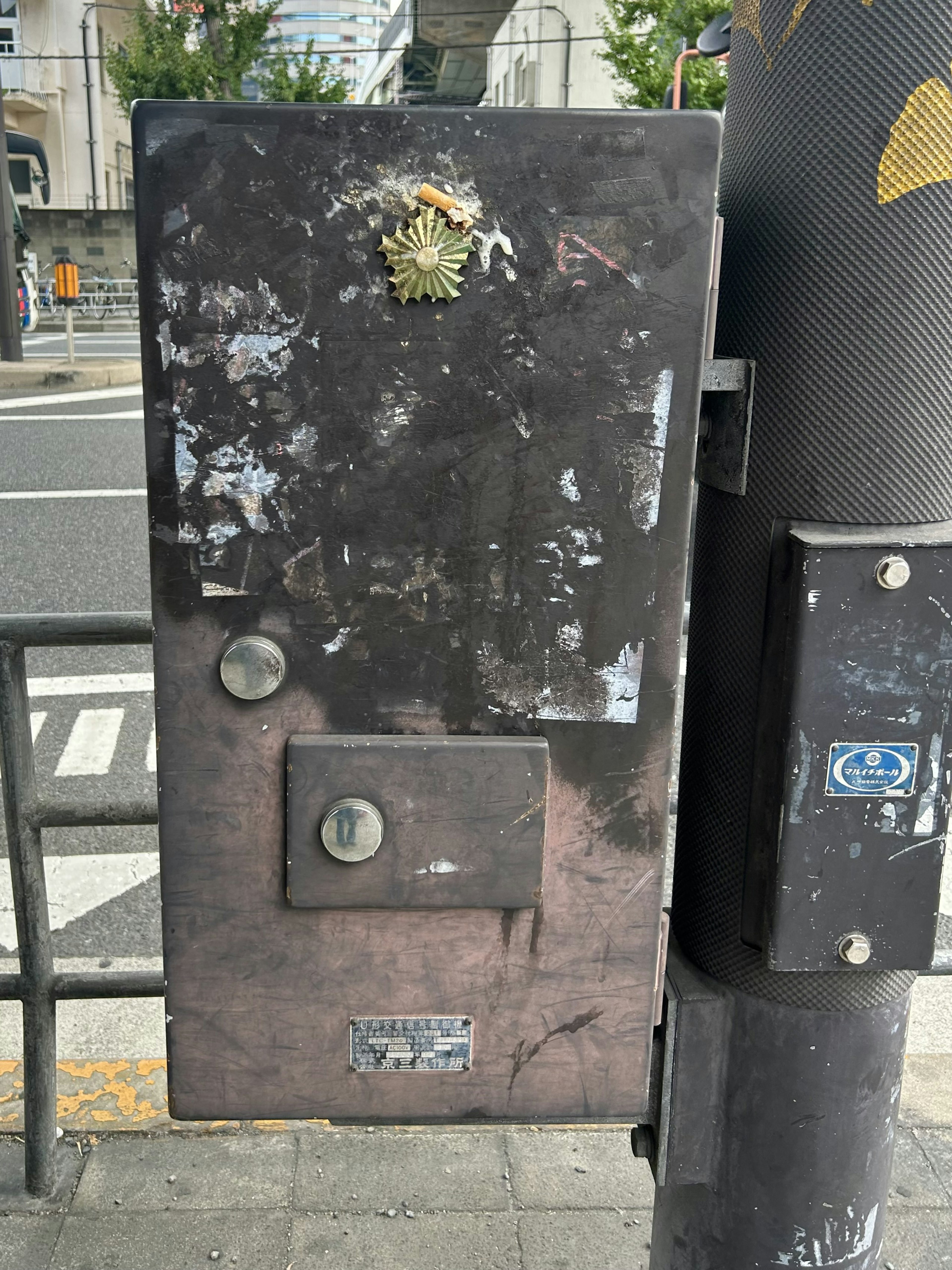 Una caja eléctrica negra desgastada con suciedad y rasguños, con una pequeña planta en la parte superior