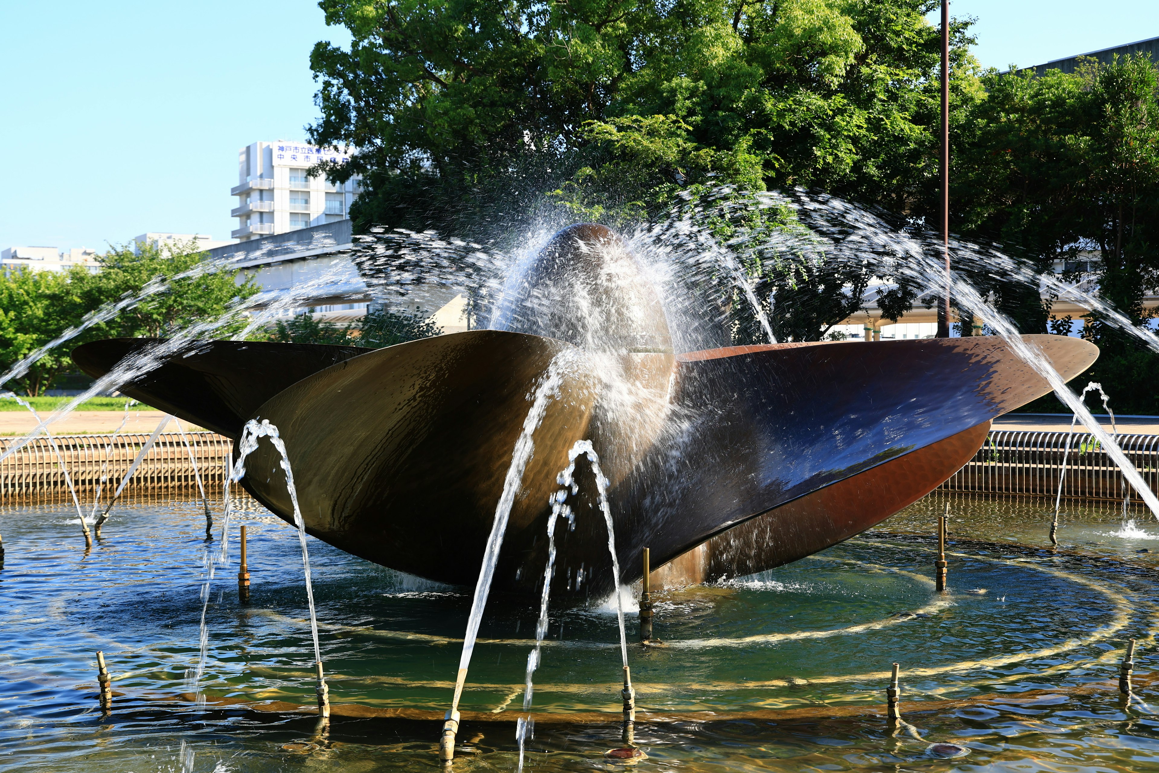 Künstlerischer Brunnen in einem Park großes bronzefarbenes Blütenblattdesign Wasser spritzt