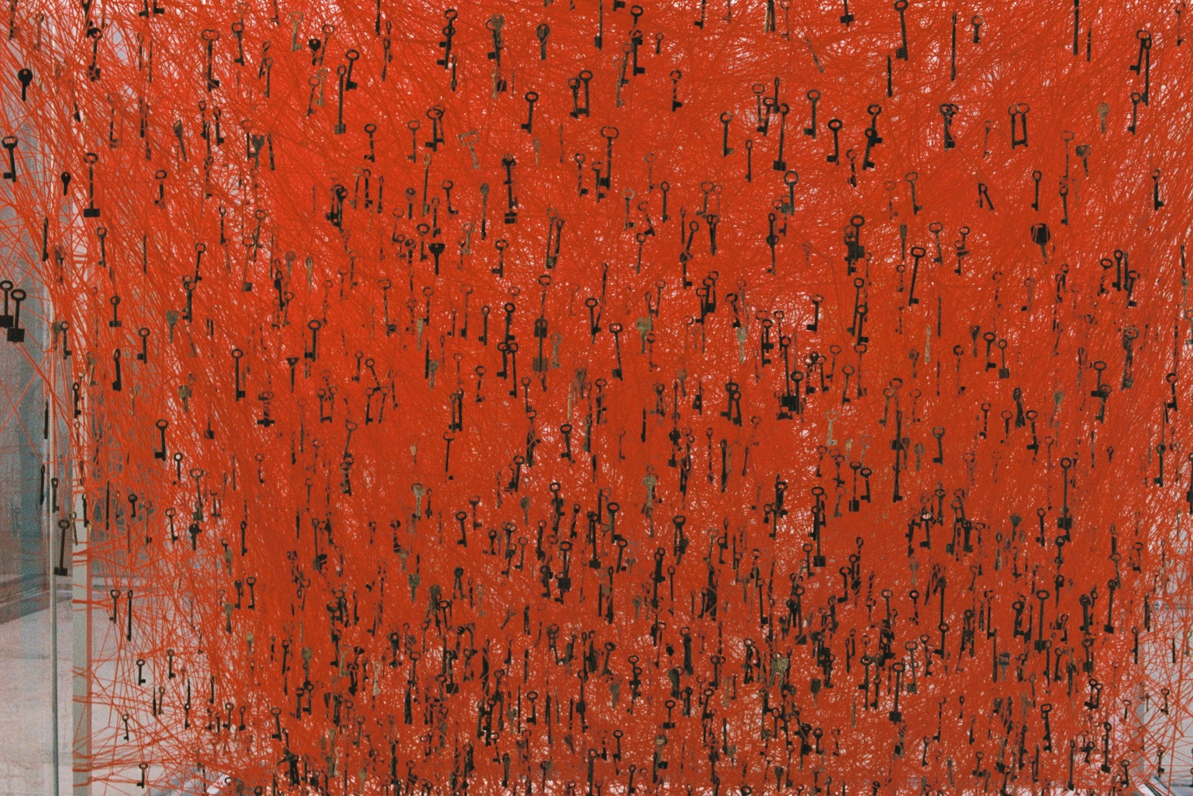 Obra de arte abstracta con un fondo rojo vibrante y líneas negras entrelazadas