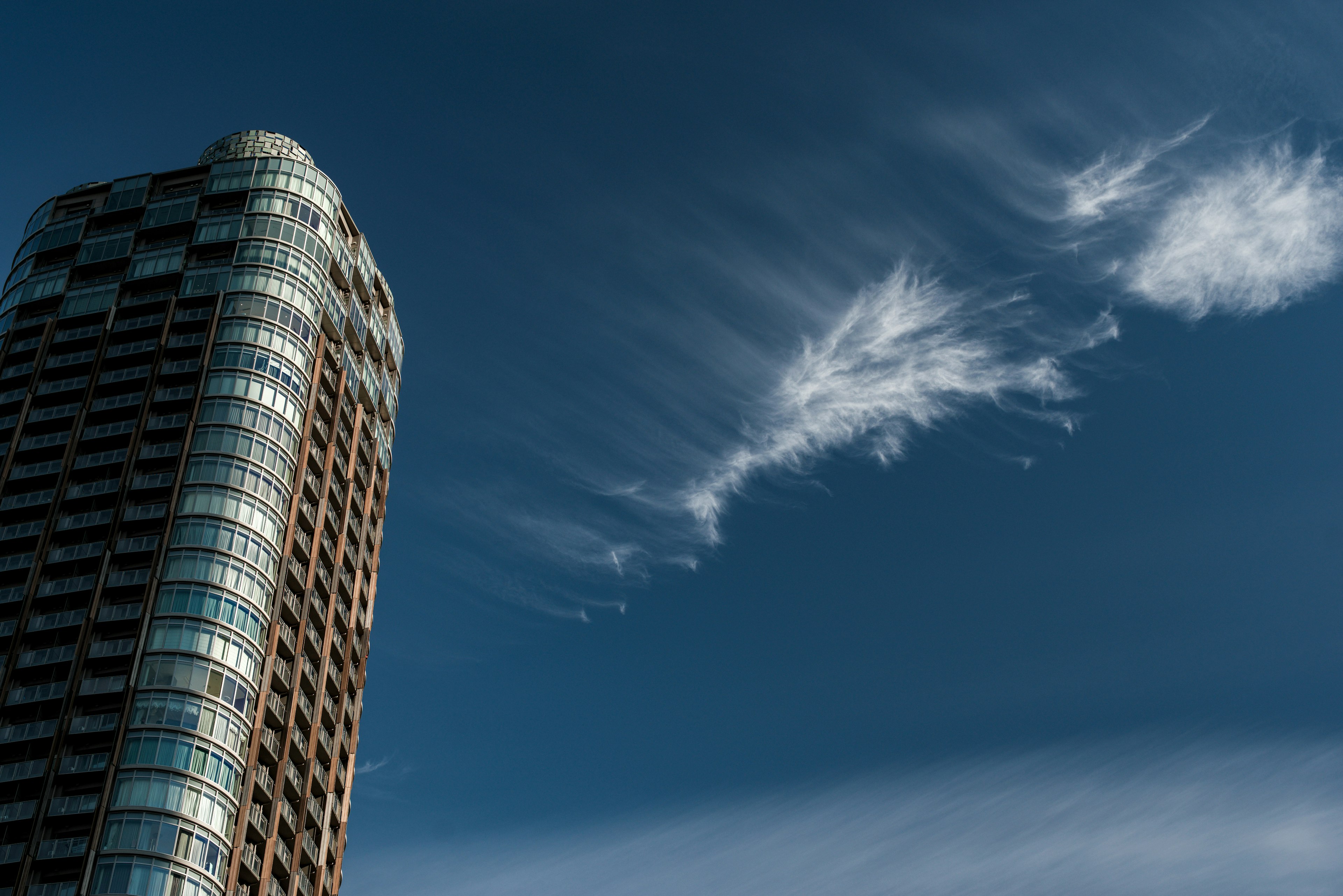 Hochhaus vor blauem Himmel mit wispy Wolken