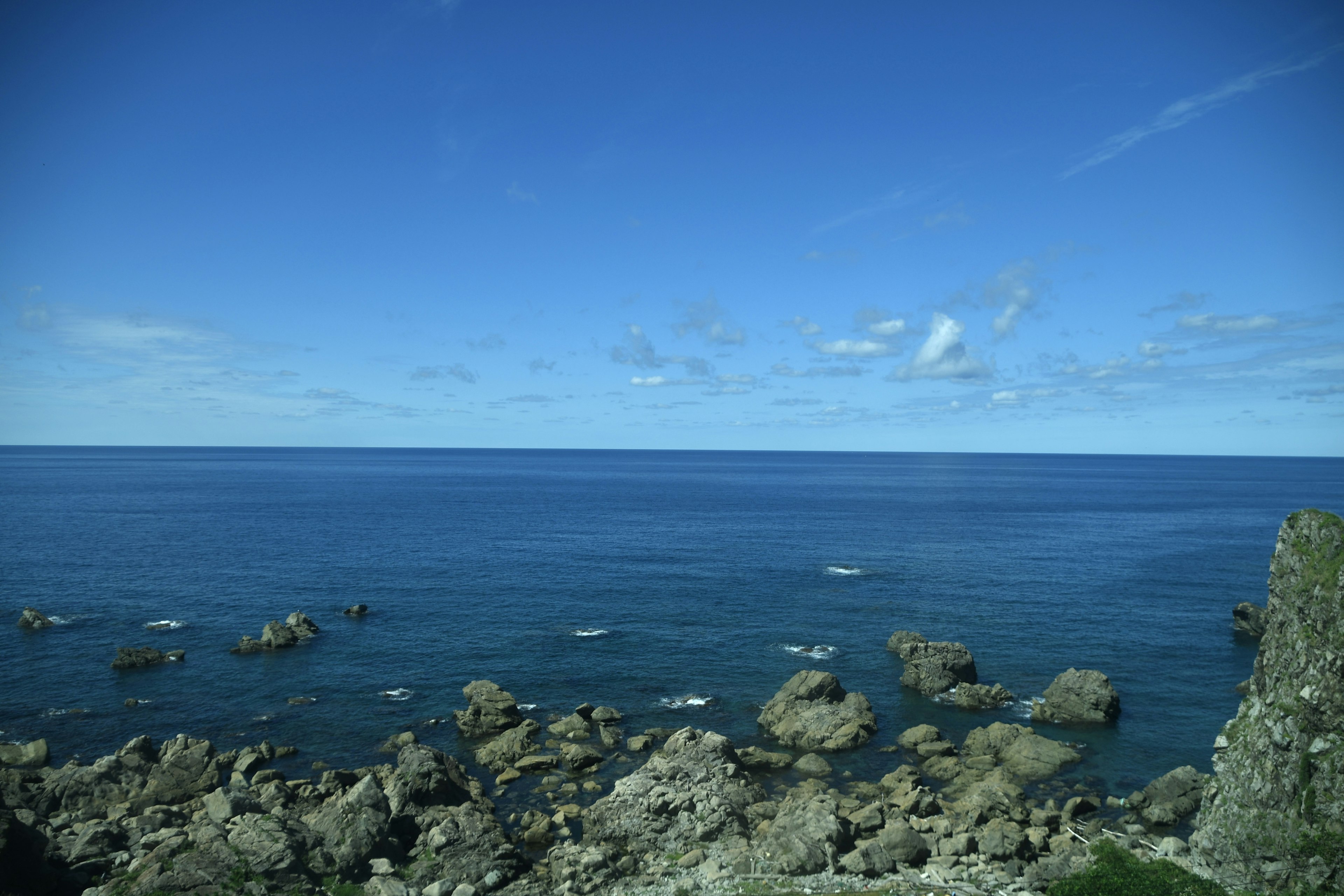 Scenic view of blue sky and calm sea with rocky shoreline