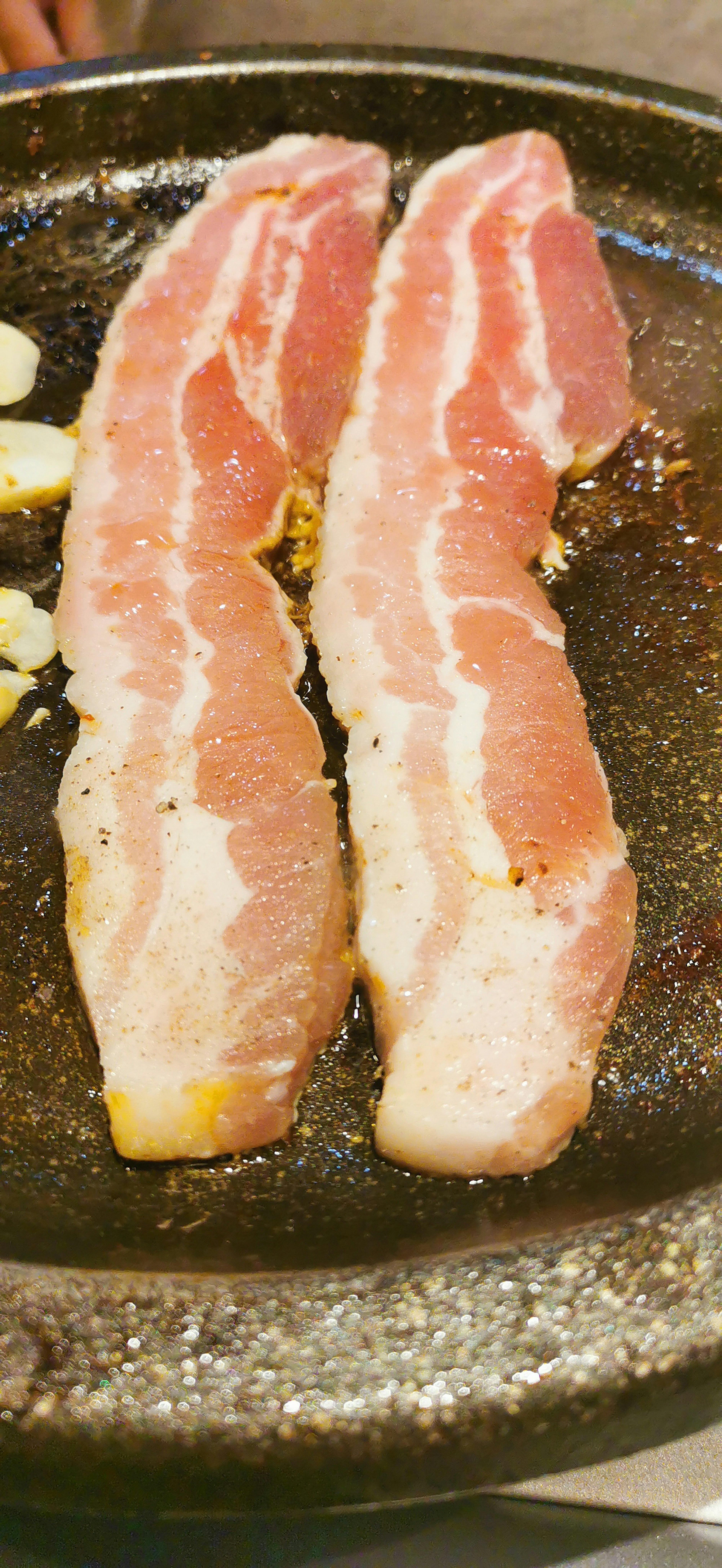 Two slices of meat cooking on a grill