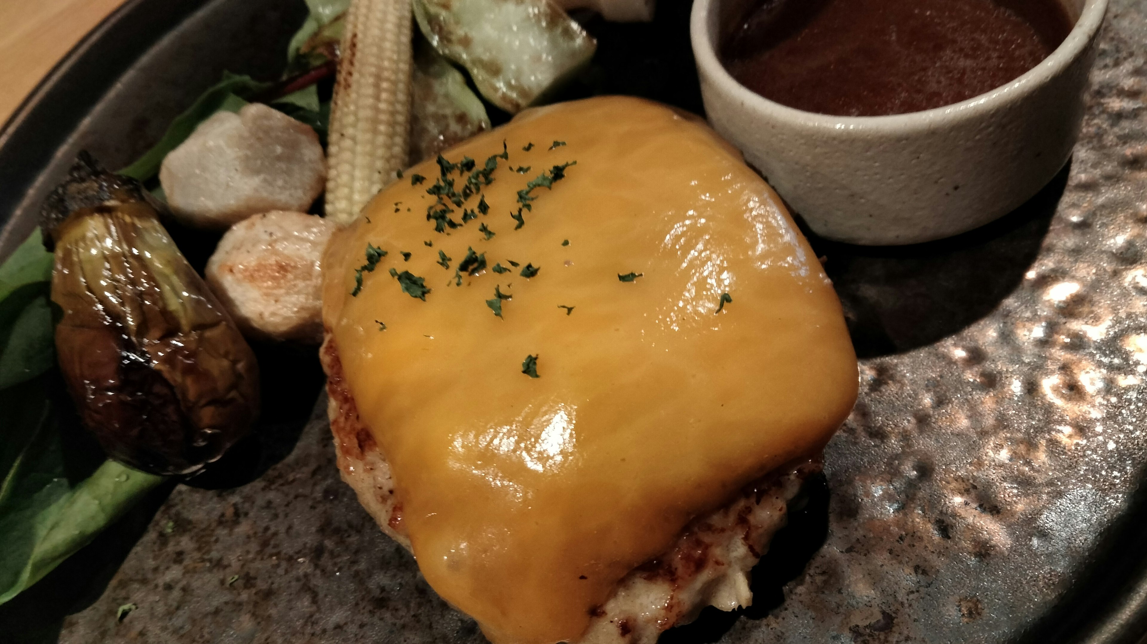 Cheeseburger topped with melted cheese accompanied by assorted vegetables