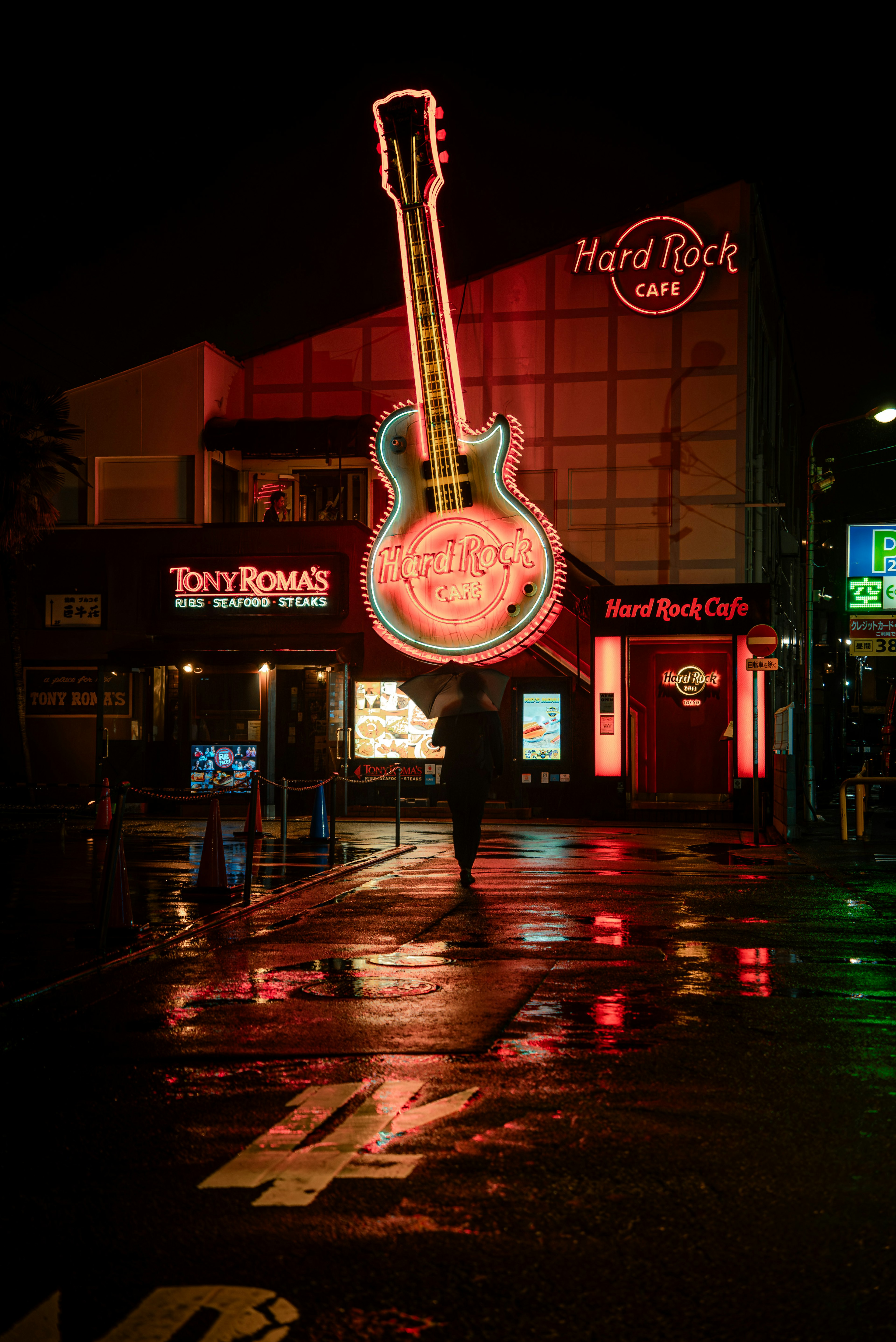 Tanda neon gitar Hard Rock Cafe dengan trotoar basah di malam hari