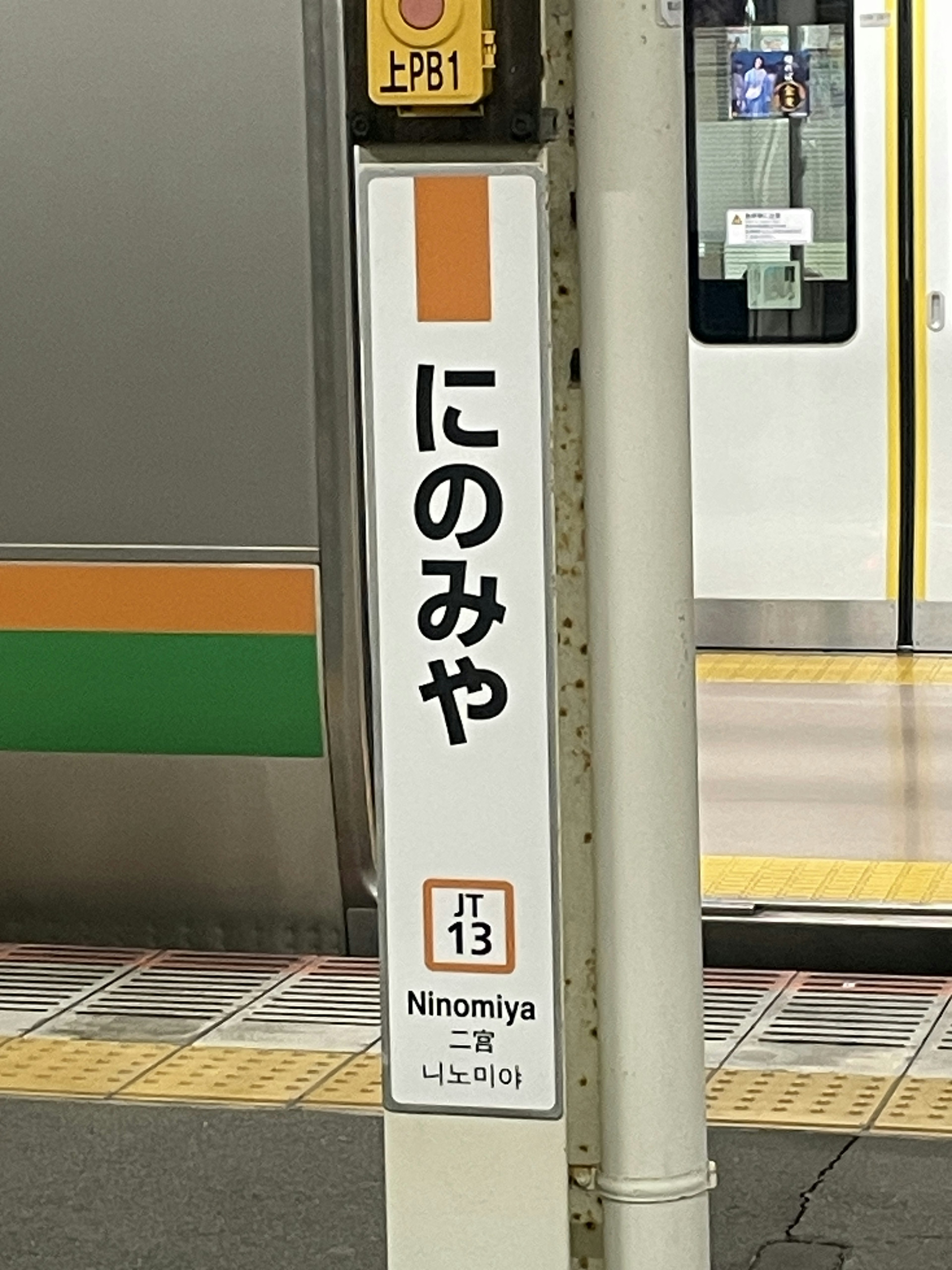 Schild der Station Ninomiya mit einem Teil des Zuges sichtbar