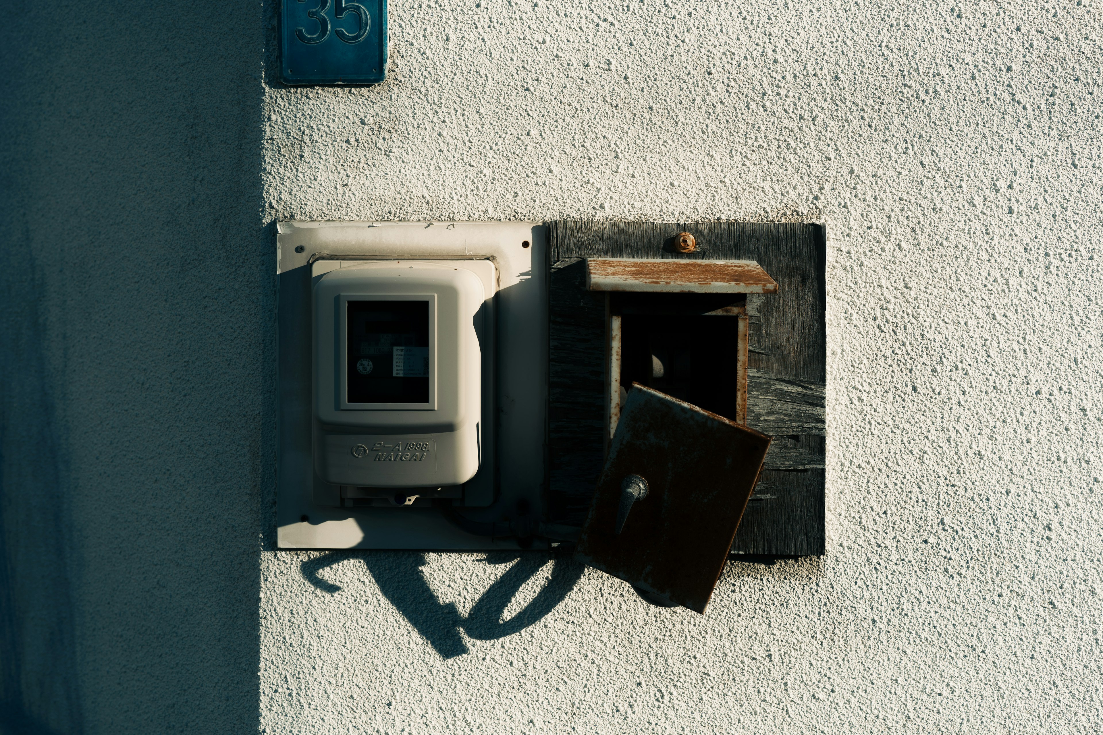 Old mailbox and electric meter mounted on a white wall