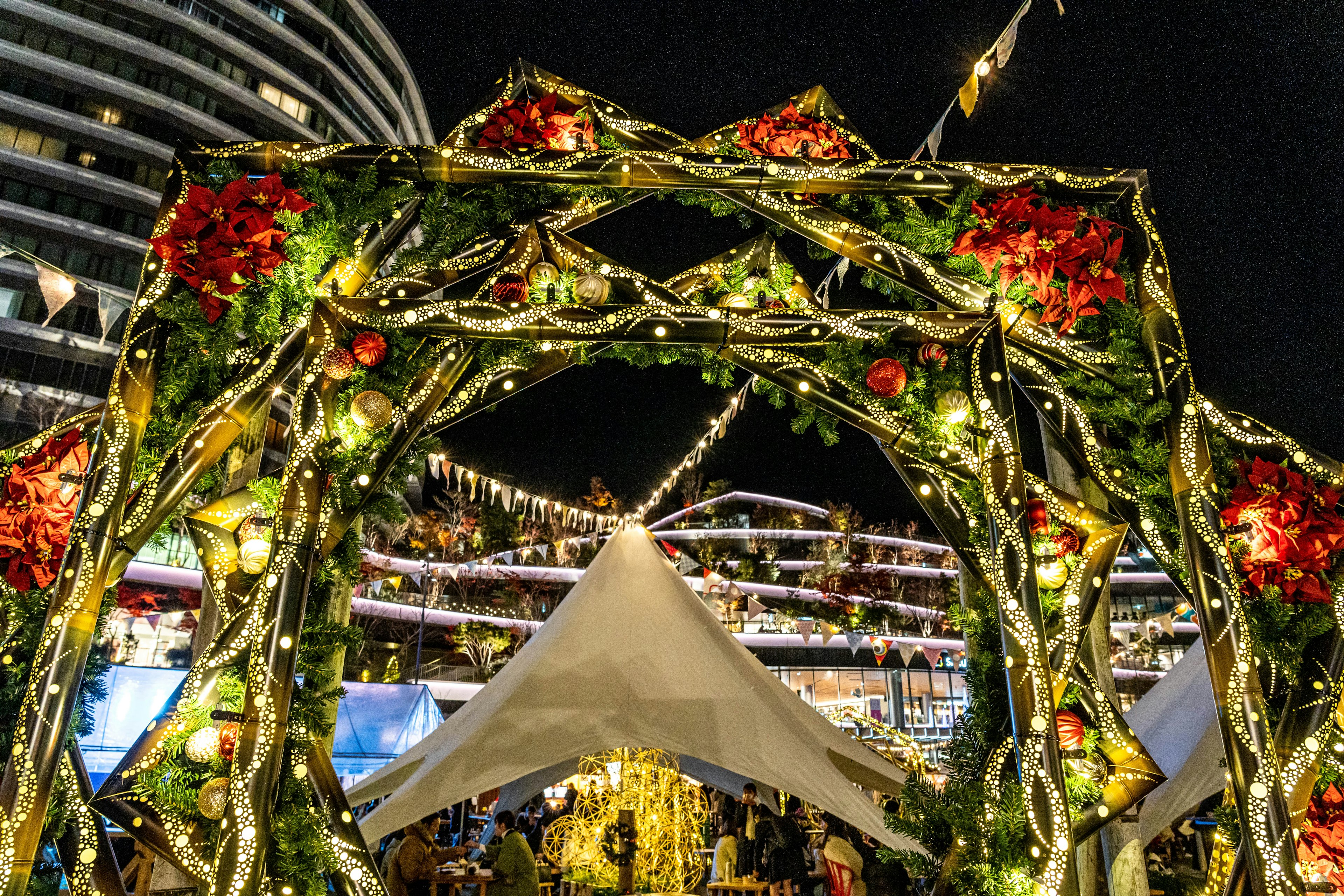 Illuminated arch adorned with flowers and decorative lights at night