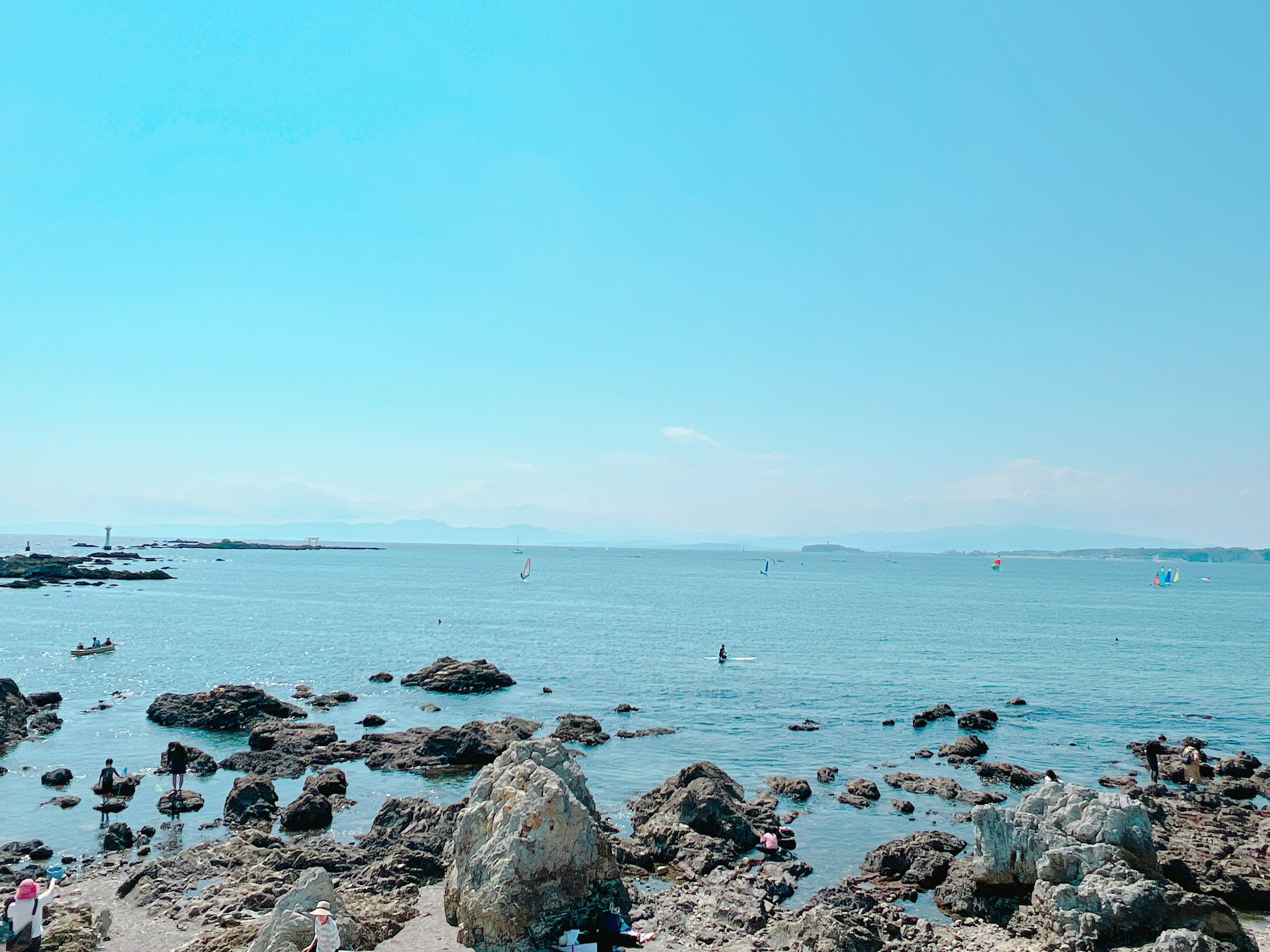 Pemandangan laut tenang di bawah langit biru dengan batu-batu tersebar