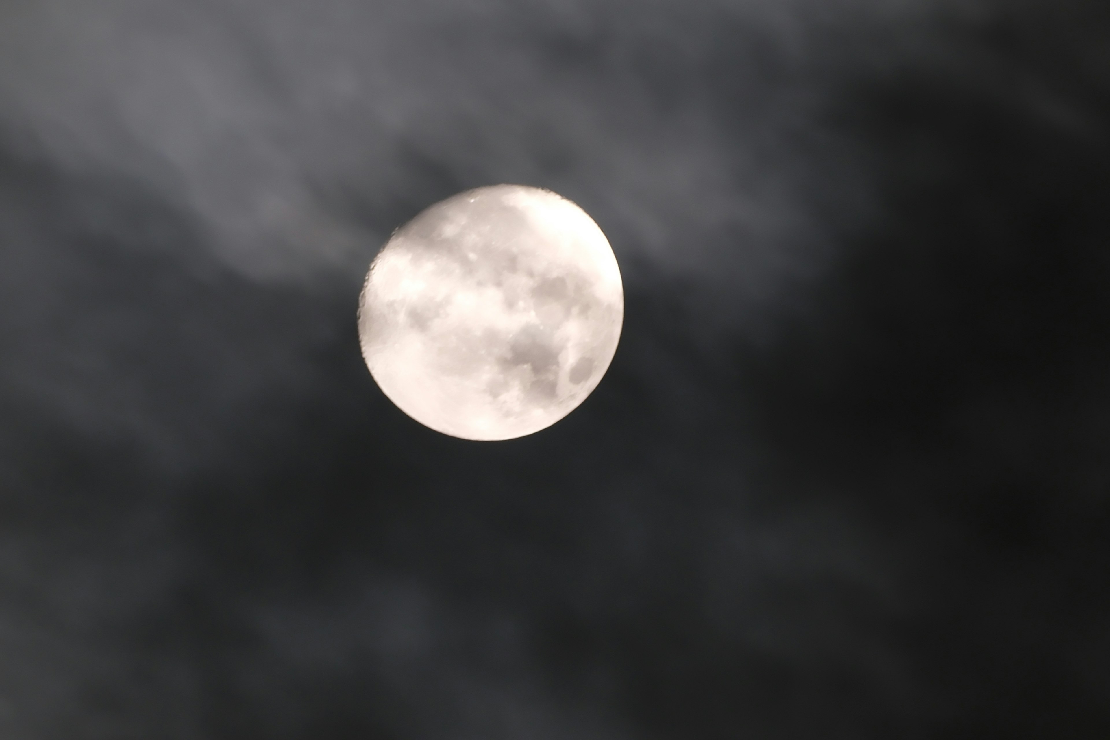 Bright moon partially obscured by dark clouds