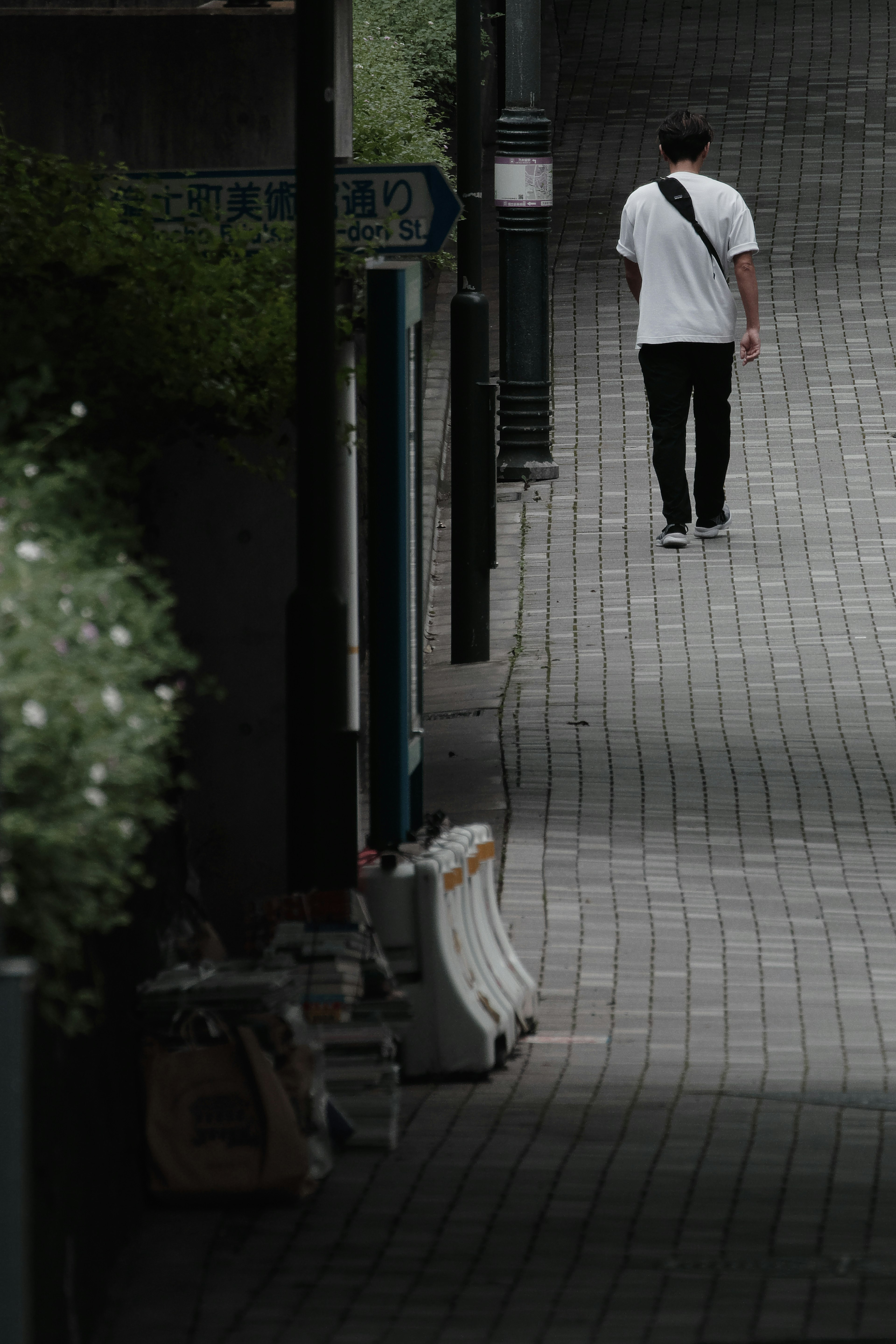 Un homme en chemise blanche marchant sur un chemin en pavés