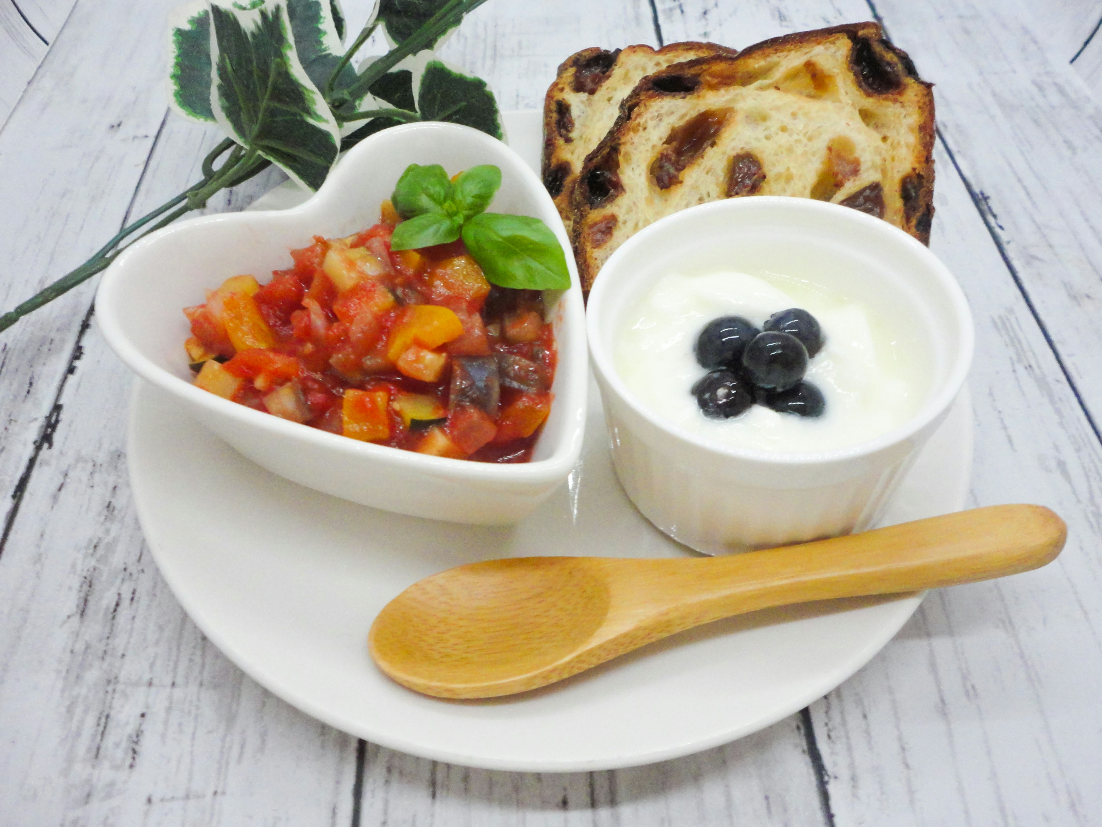 Heart-shaped bowl with vegetable salad and cream with blueberries wooden spoon and toast on a plate