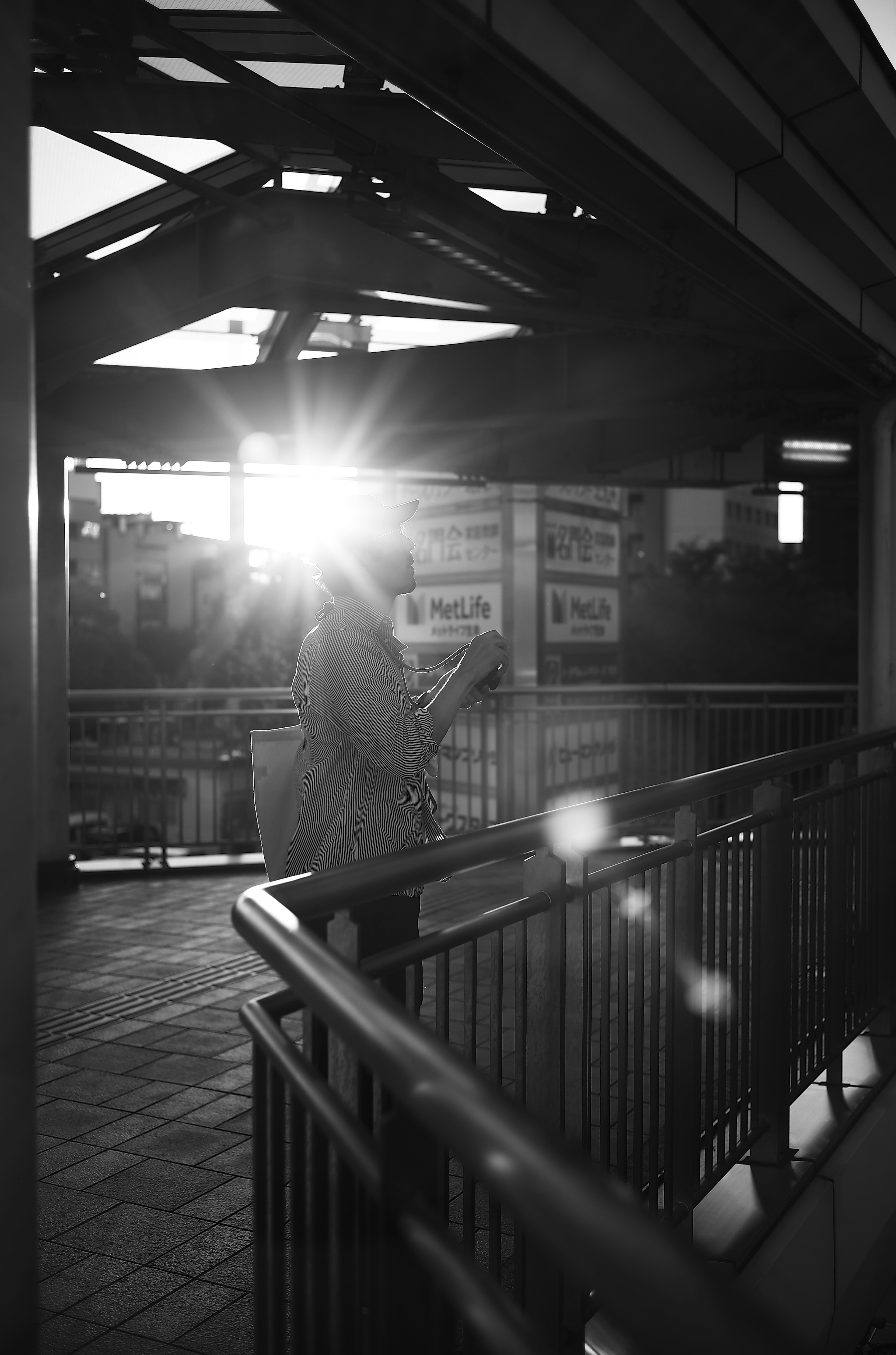 Black and white photo of a person with arms raised sunlight shining from behind