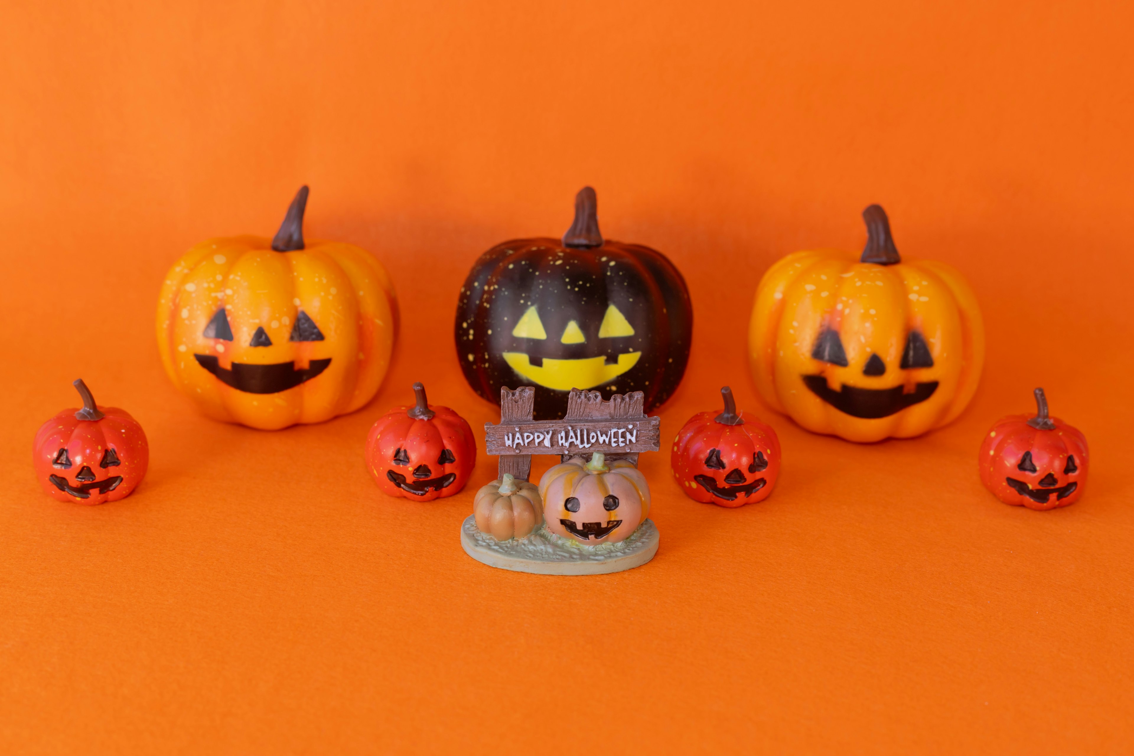 Calabazas de Halloween con caras sonrientes sobre un fondo naranja que incluye calabazas grandes y pequeñas