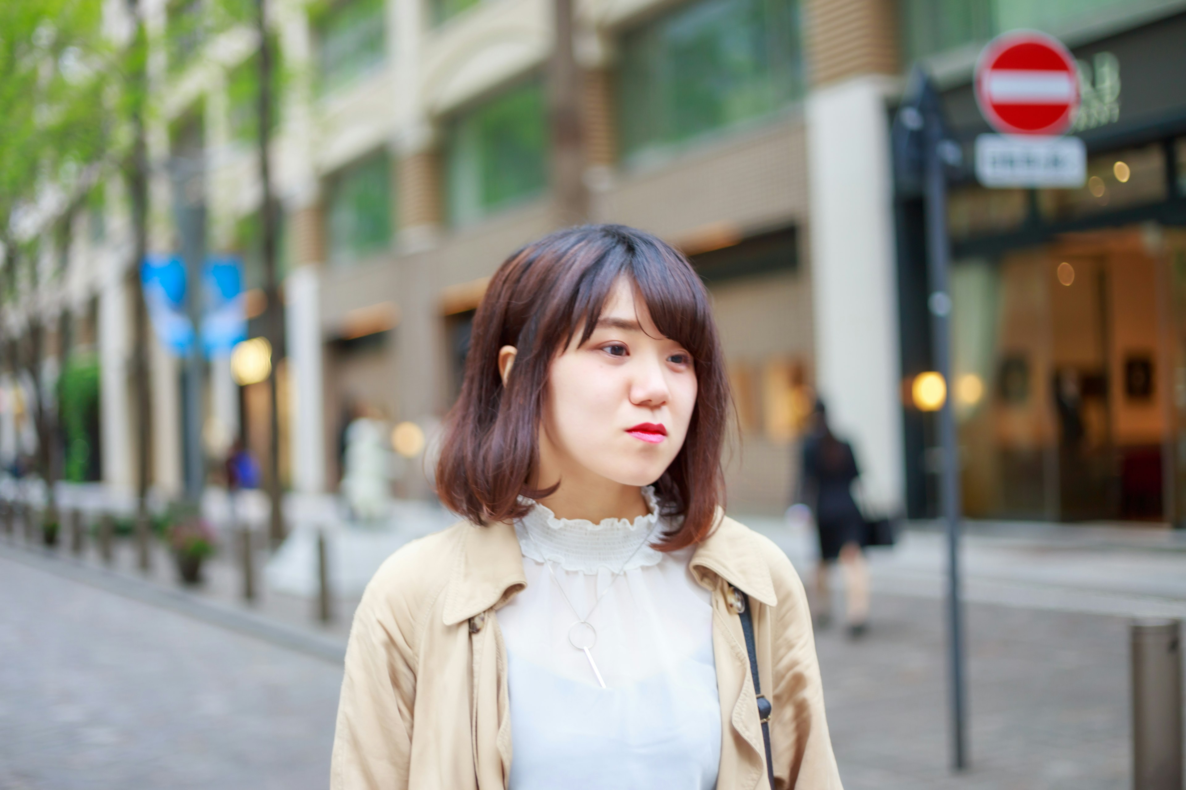 女性が街中で立っている様子 色合いは明るく 街並みが背景にある