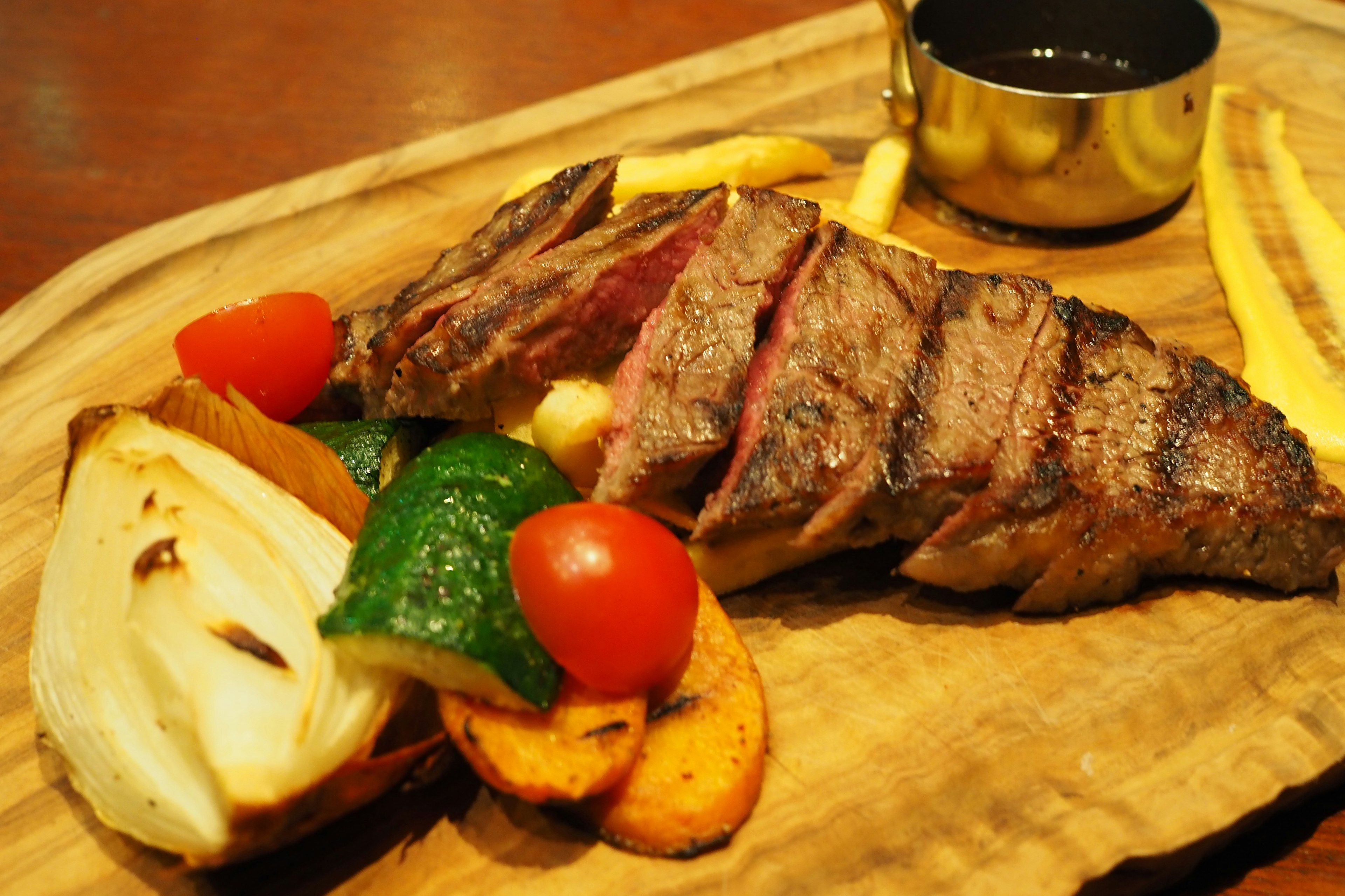 Grilled steak slices served with colorful vegetables and dipping sauce