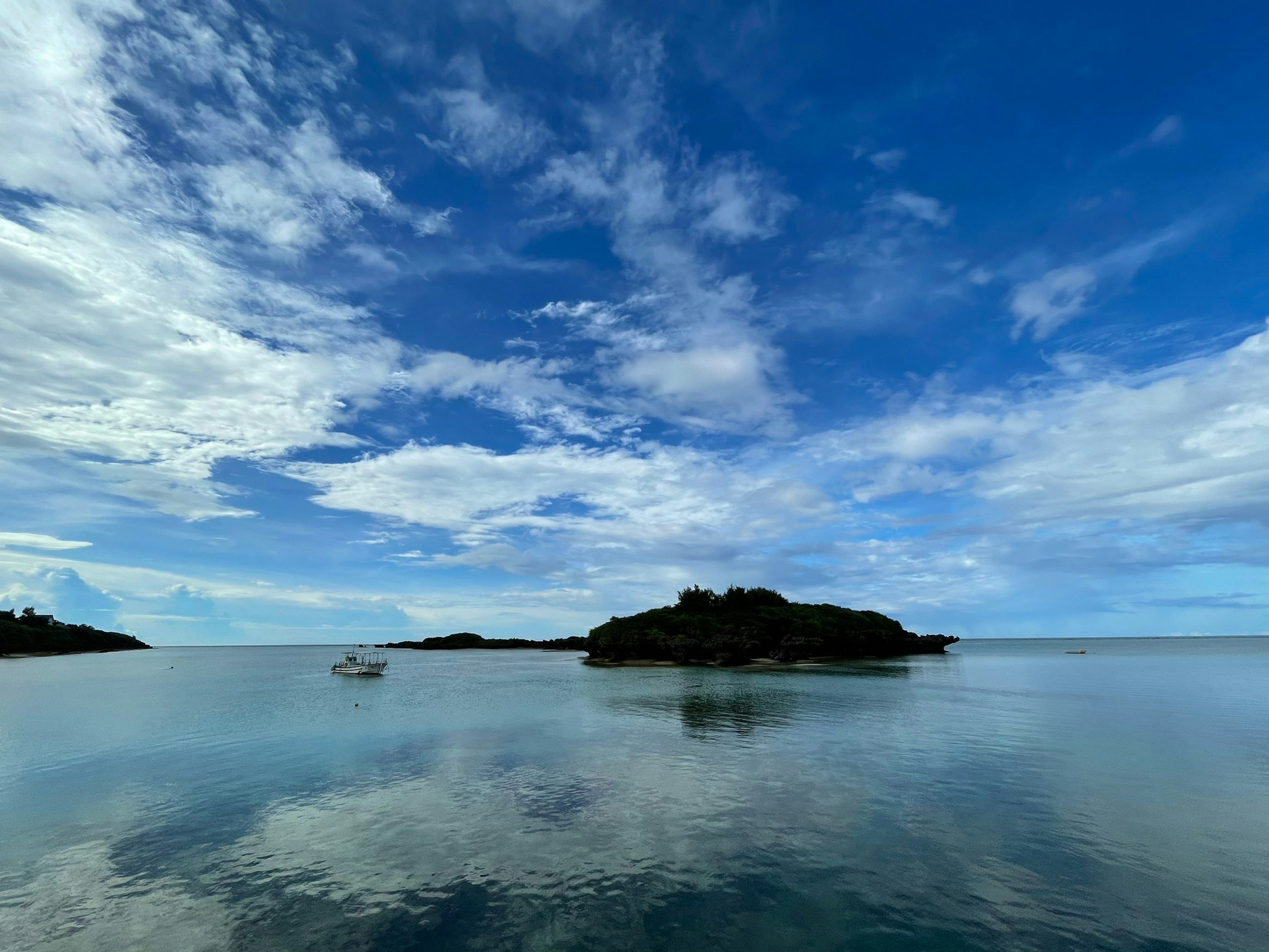 Malersiche Aussicht auf blauen Himmel mit weißen Wolken über ruhigem Wasser mit einer kleinen Insel