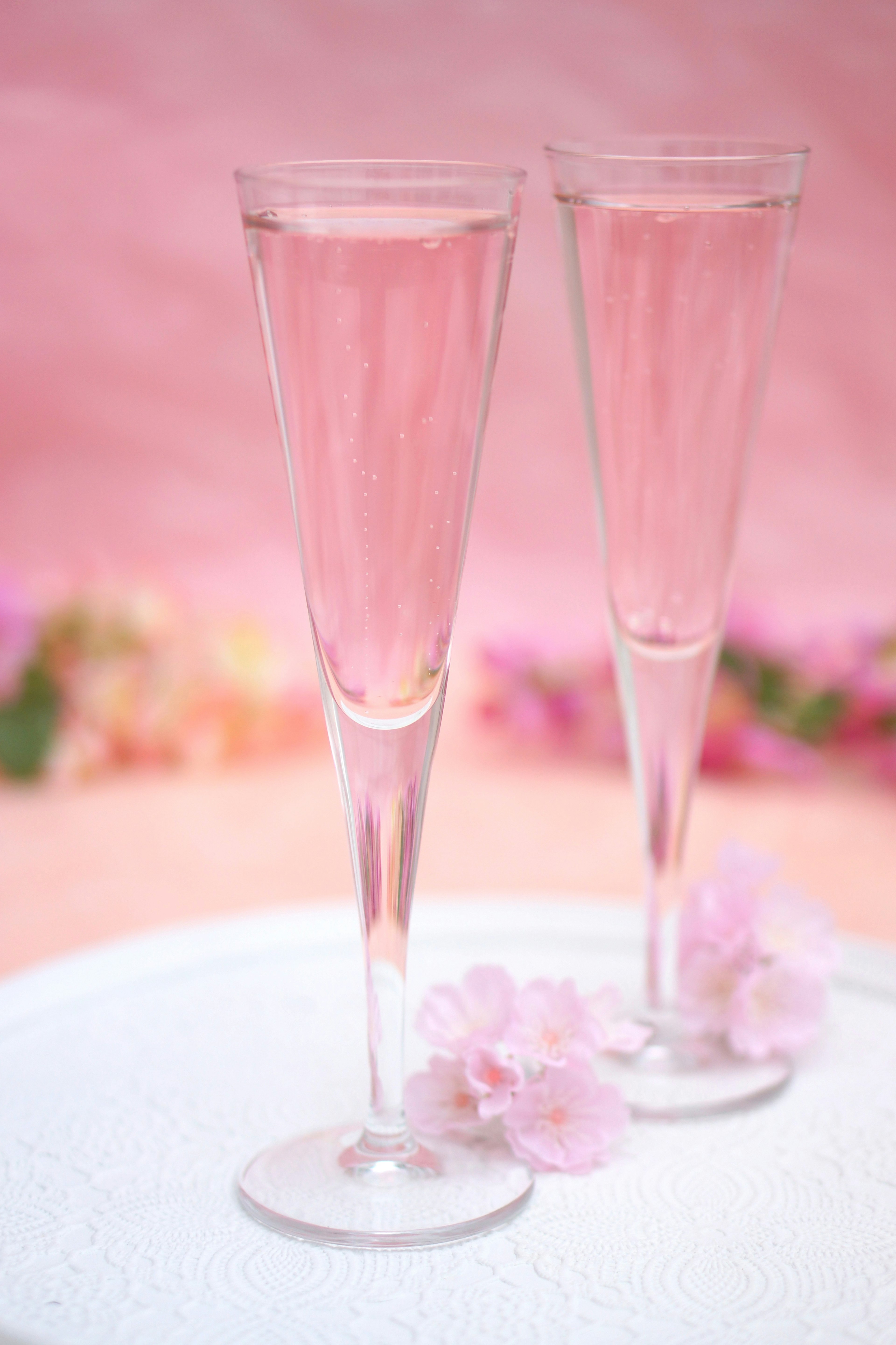 Two glasses filled with pink drink and flower petals