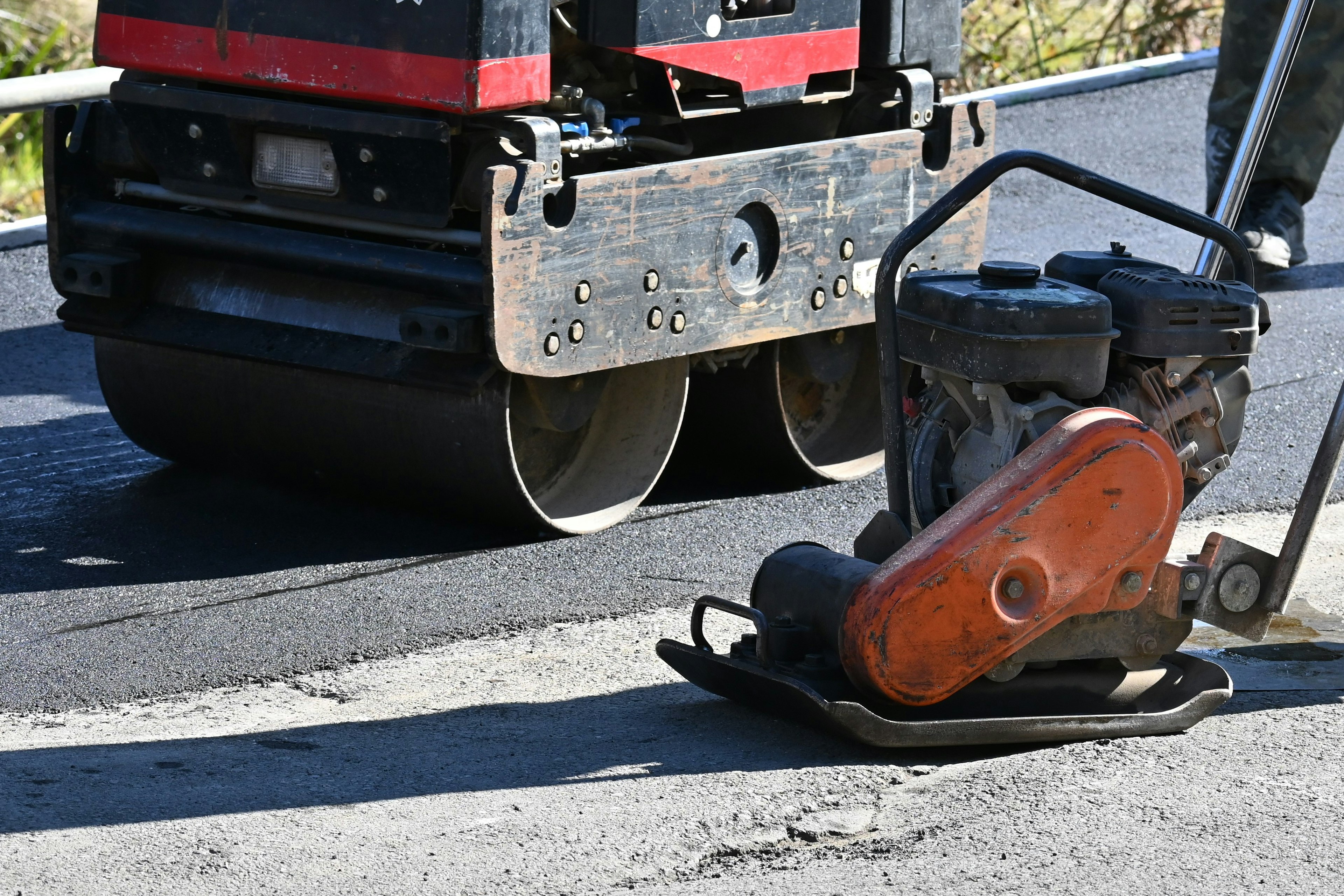 Compactador de placa vibratoria y rodillo de asfalto en un sitio de construcción