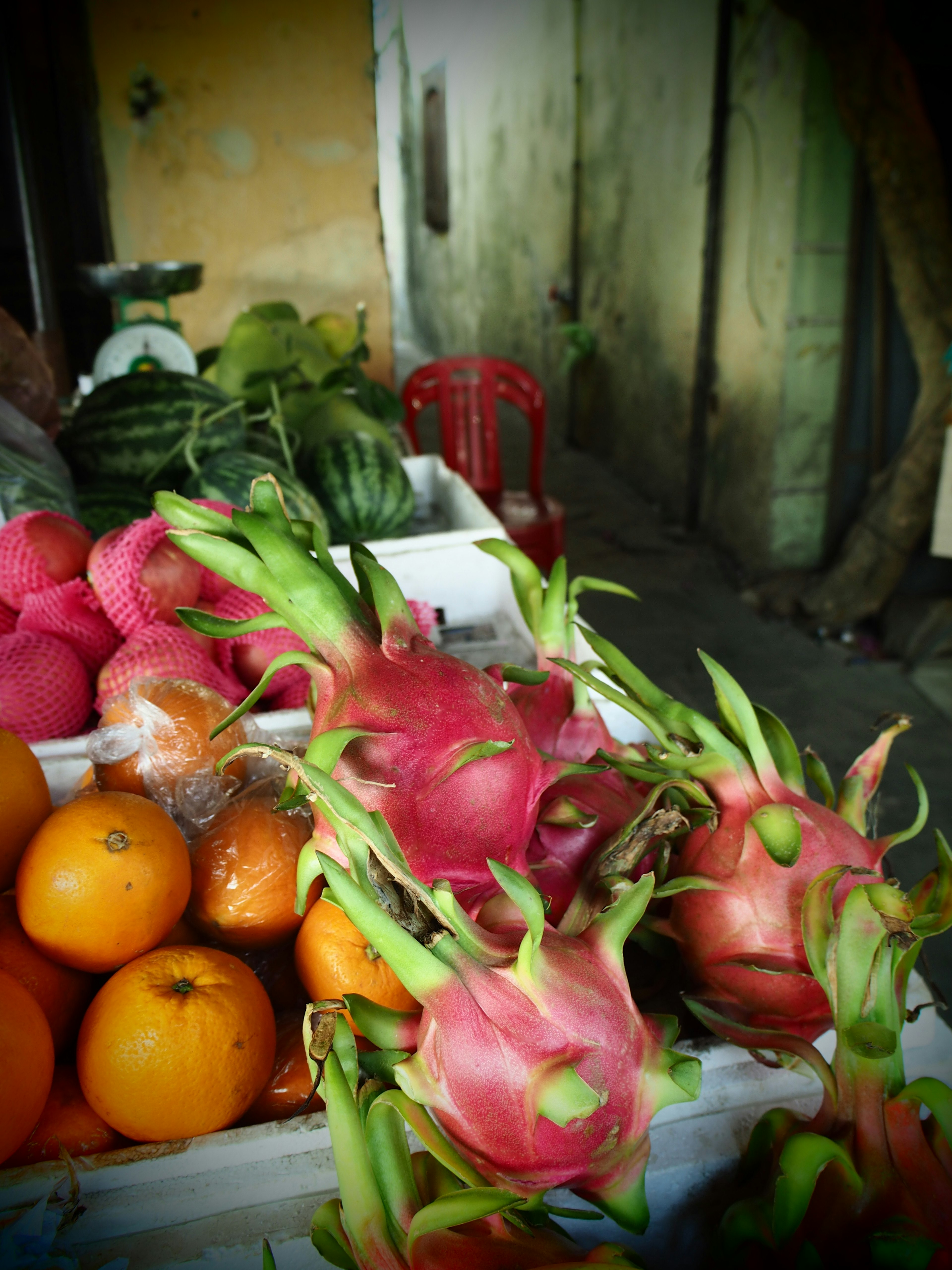 A display of dragon fruit and oranges at a market